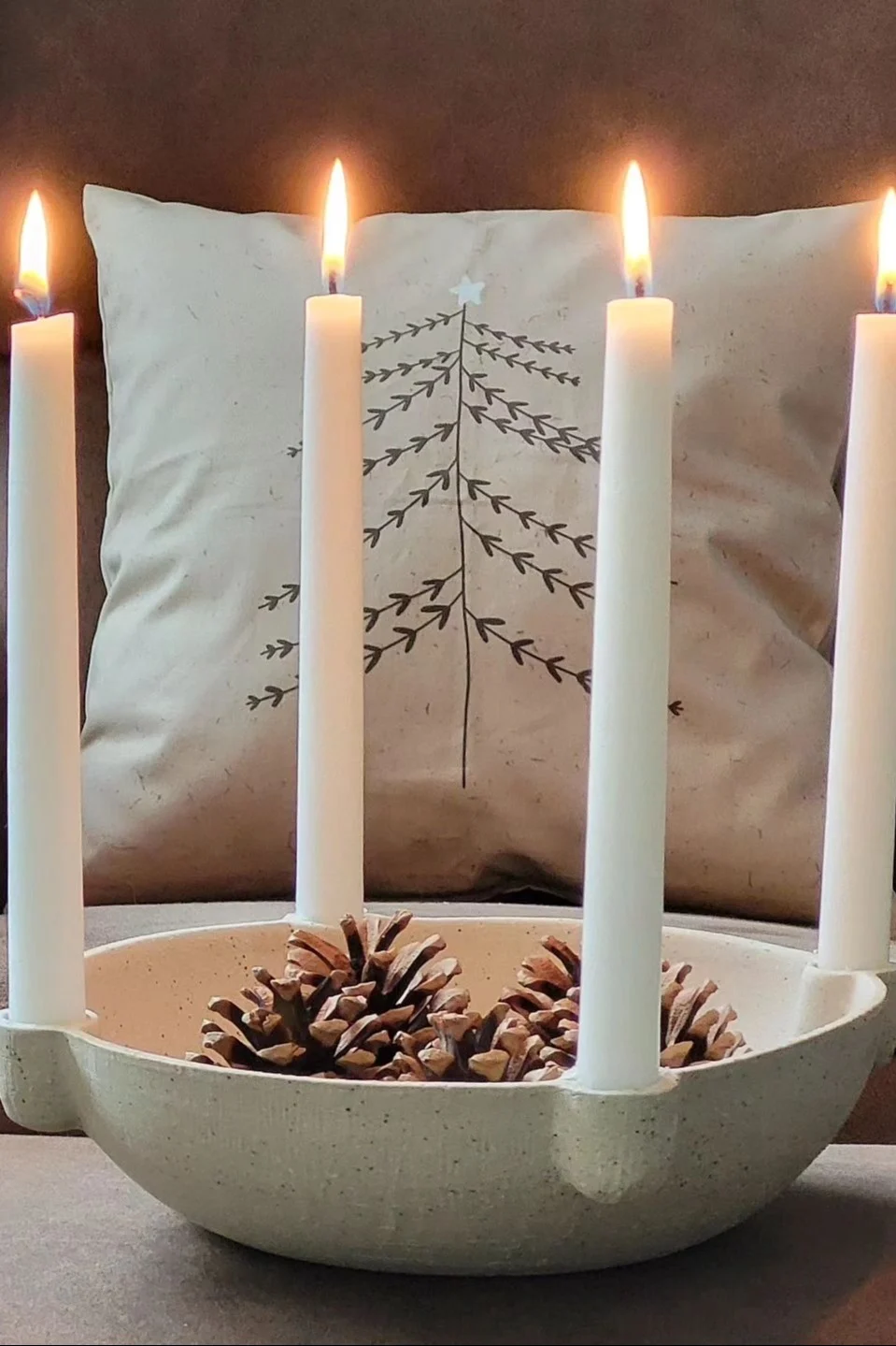 Un portavelas Bowl de Ferm Living decorado con piñas.