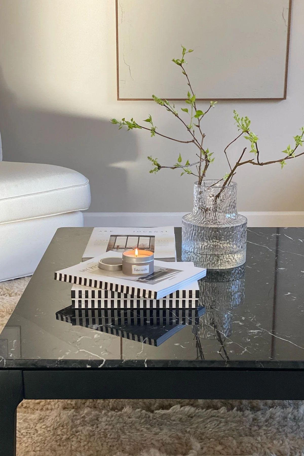 Una mesa de centro negra, decorada con libros y el jarrón Skrufs Kolonn.