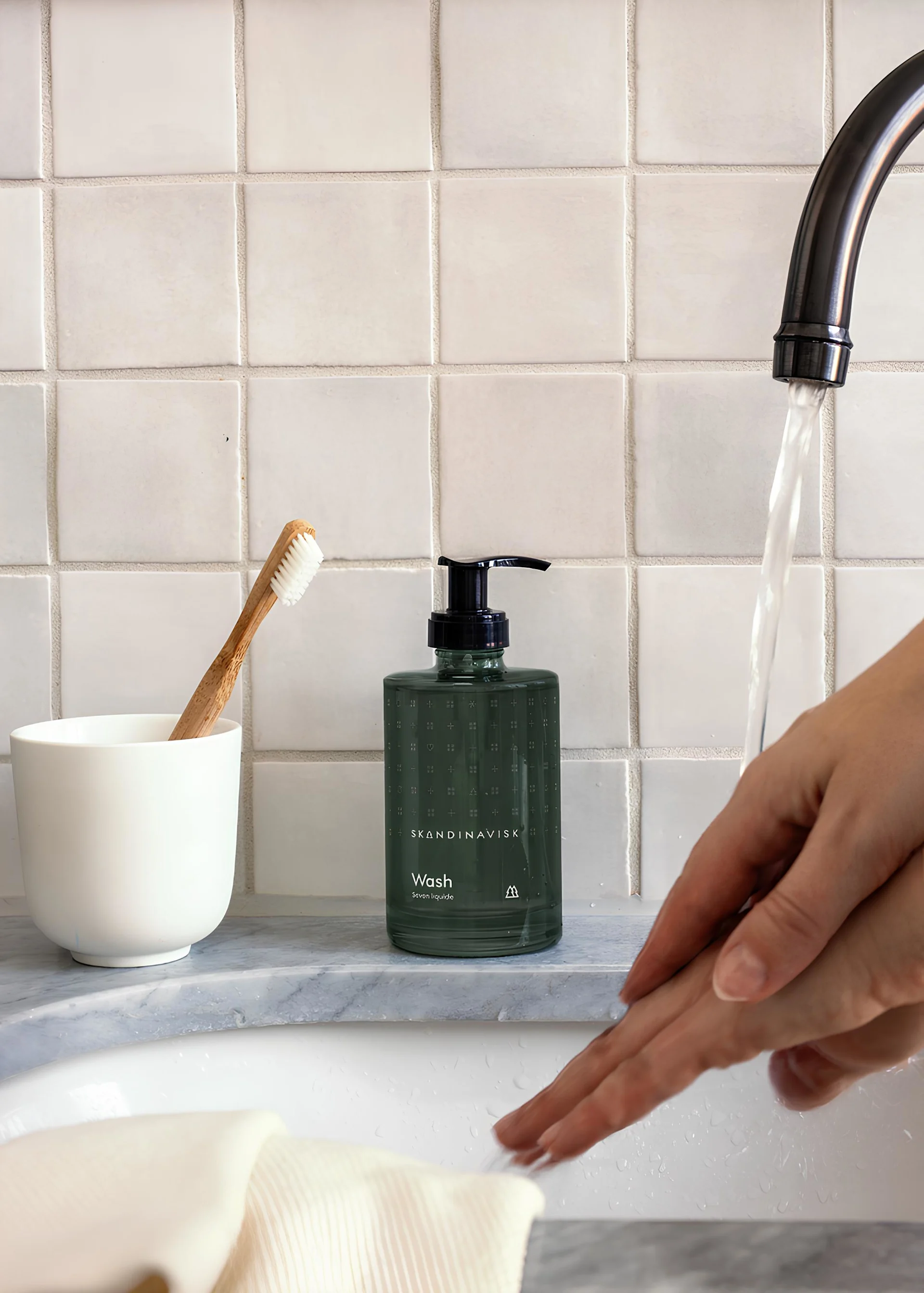 Regalo para el Día de San Valentín: regala momentos de spa. Aquí se muestra el jabón Skog de Skandinavisk sobre un lavabo, mientras una persona se lava las manos.