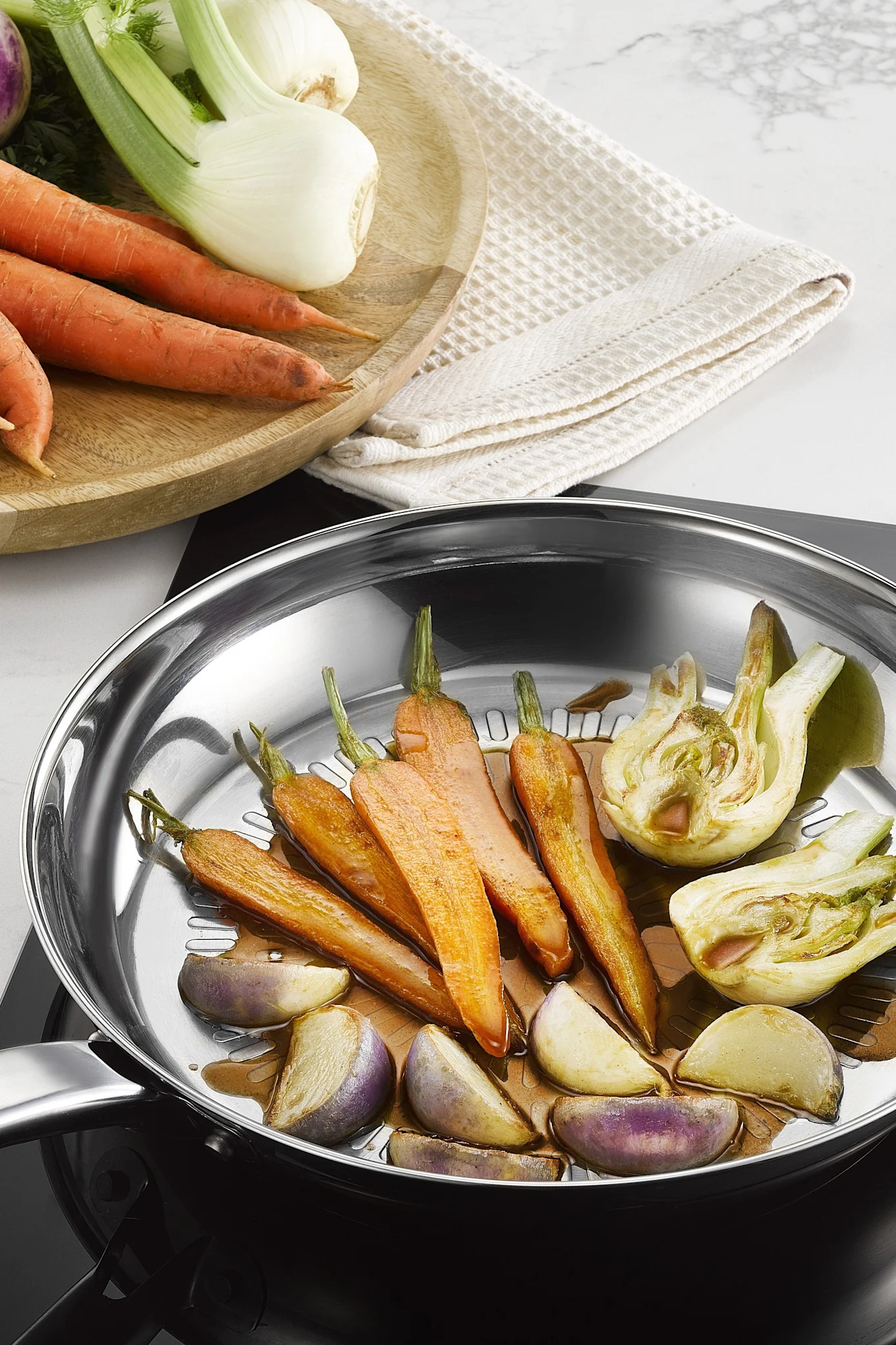 Varias verduras se fríen en la sartén de acero inoxidable Intuition Techdome de Tefal.