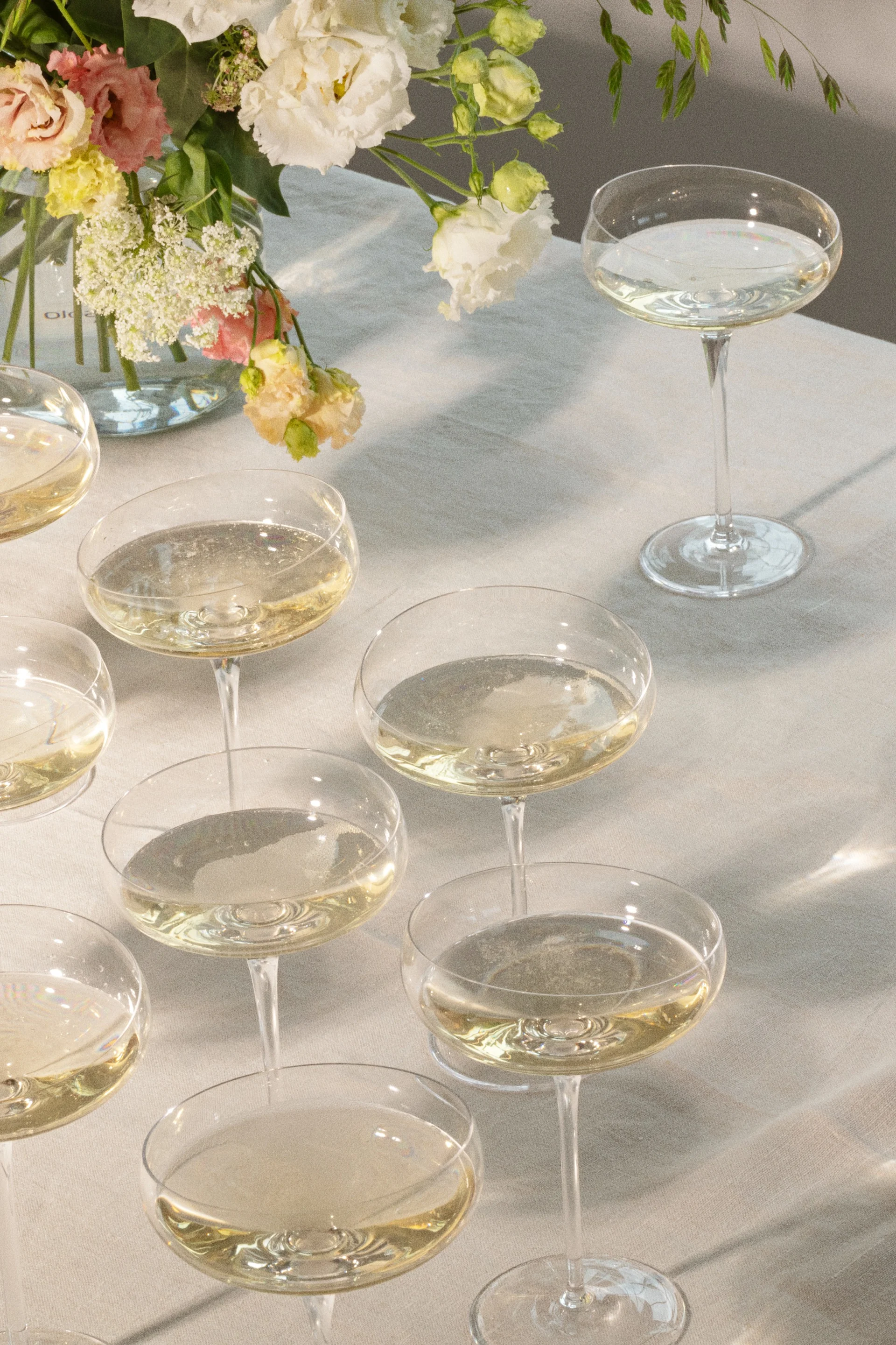 Copas de champán con bebidas espumosas en una mesa con arreglo floral.