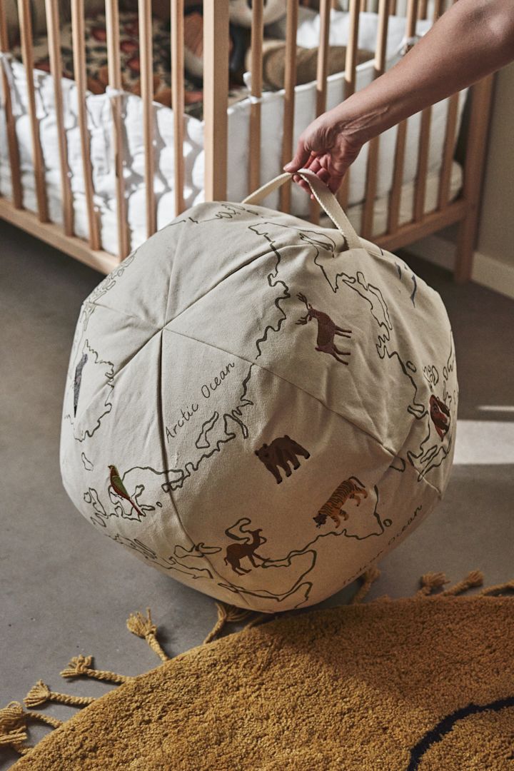 Otro detalle interior práctico y decorativo para la habitación infantil el puf The World de Ferm Living, con estampado bordado y práctico asa para colgar.