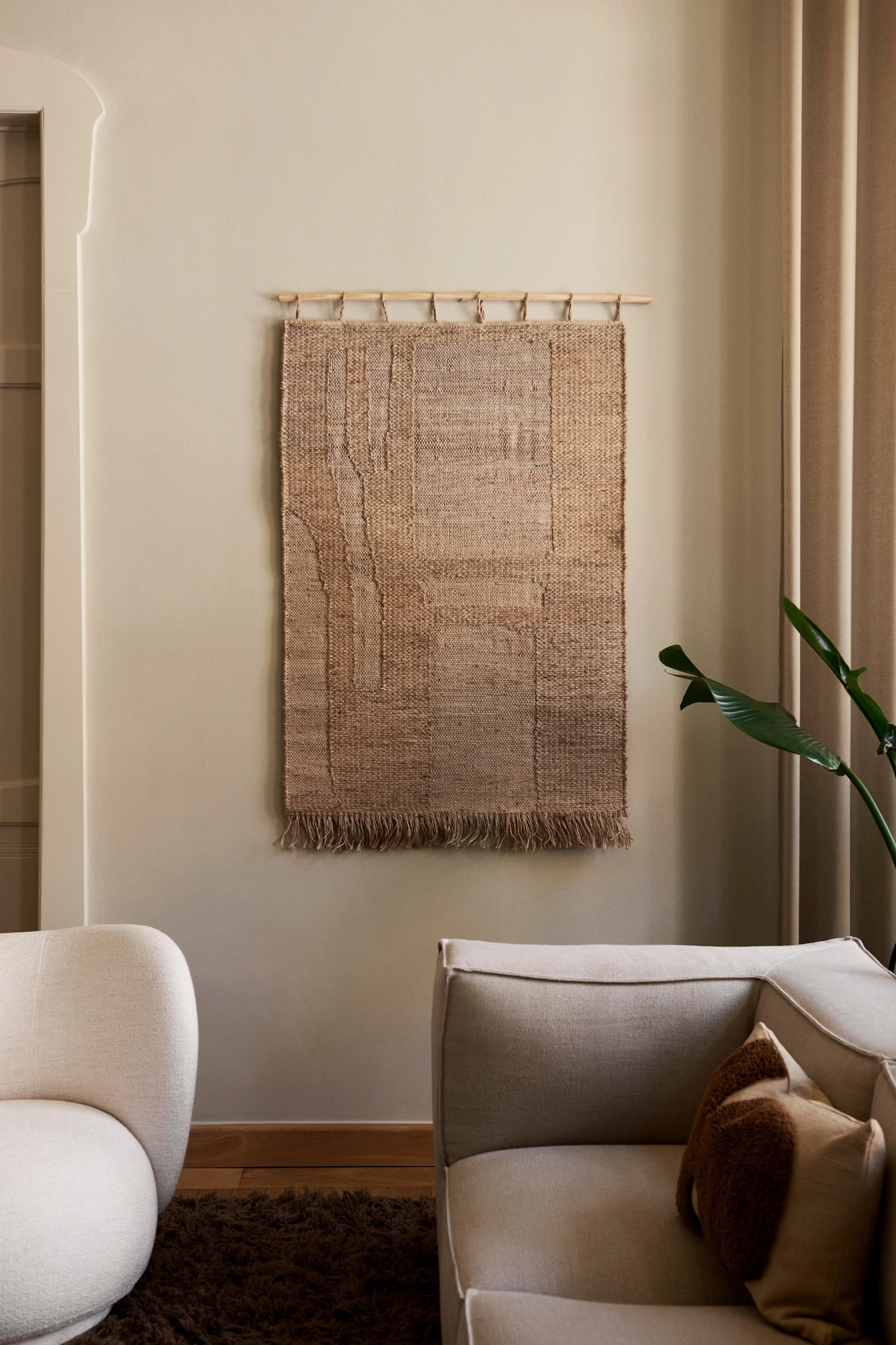 Decora la pared con el accesorio decorativo Harvest de Ferm Living, que aquí cuelga en una pared neutra del salón. 