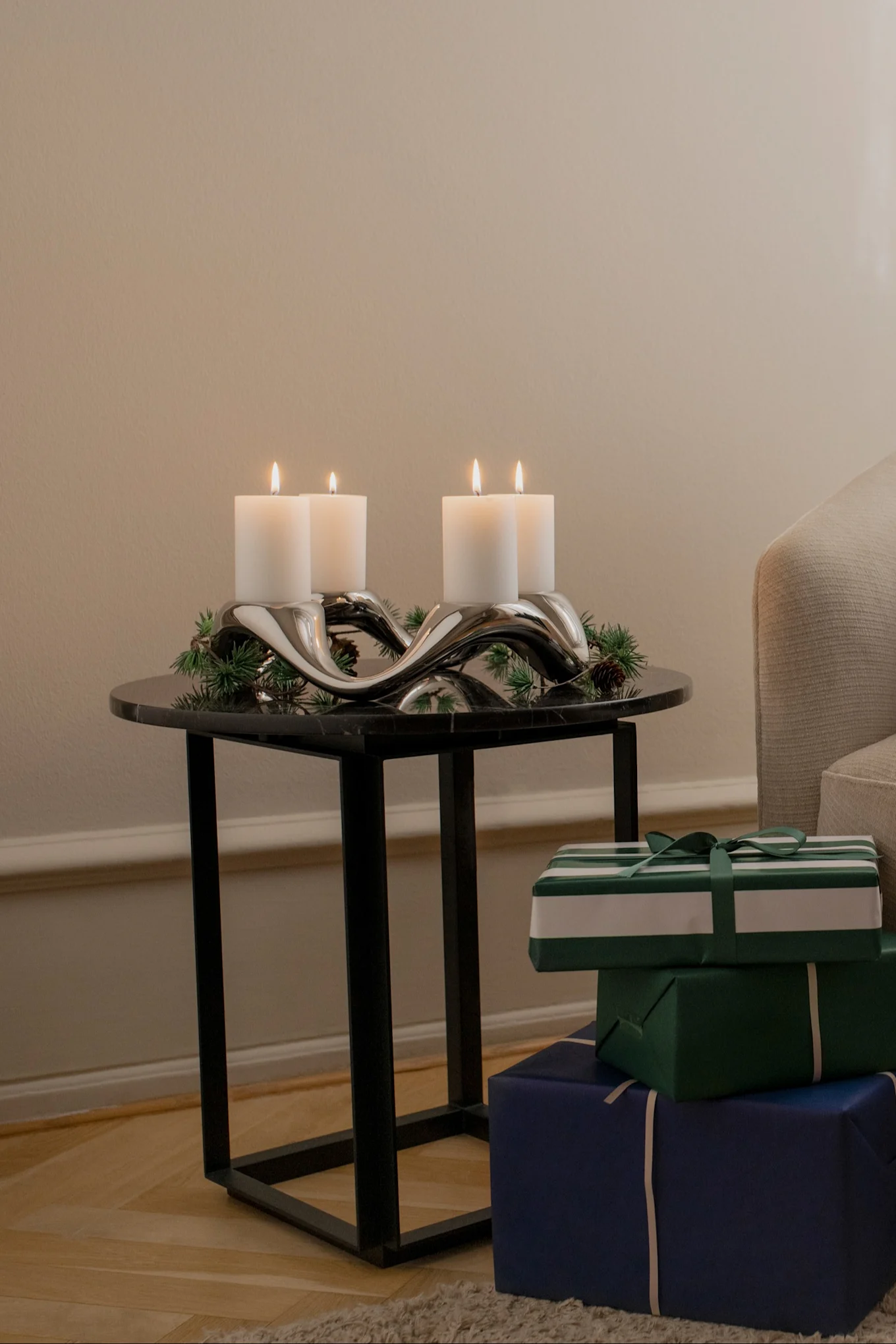 Sobre una mesa auxiliar se encuentra el portavelas Cobra de Georg Jensen, decorado con ramas de abeto.