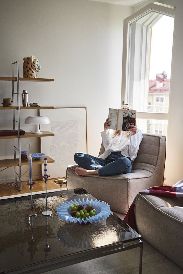 Decorar la sala de estar con piezas llamativas de Byon crea un hogar personal y ecléctico, lleno de alegría, formas y colores. Aquí el cuenco Lori en azul claro, el jarrón Cheetah, la copa de champán Opacity, el cuadro Embrace y la linterna con vela Lara.