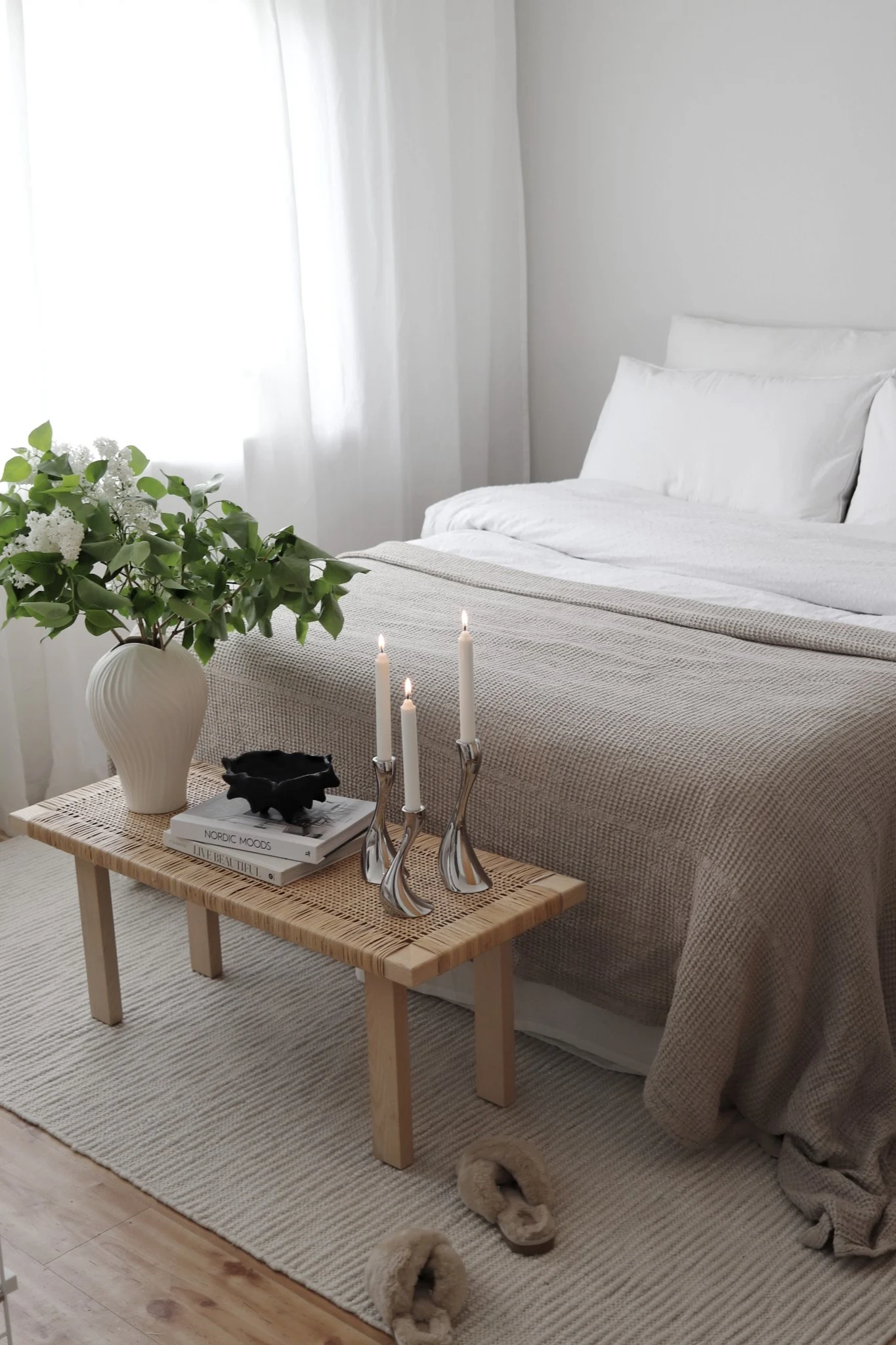 Alfombras para el dormitorio: la alfombra de lana blanca Pebble de Scandi Living está colocada a medio camino bajo la cama, y a los pies de la cama hay un banco pequeño decorado con una planta y velas. @hemmahosfalk