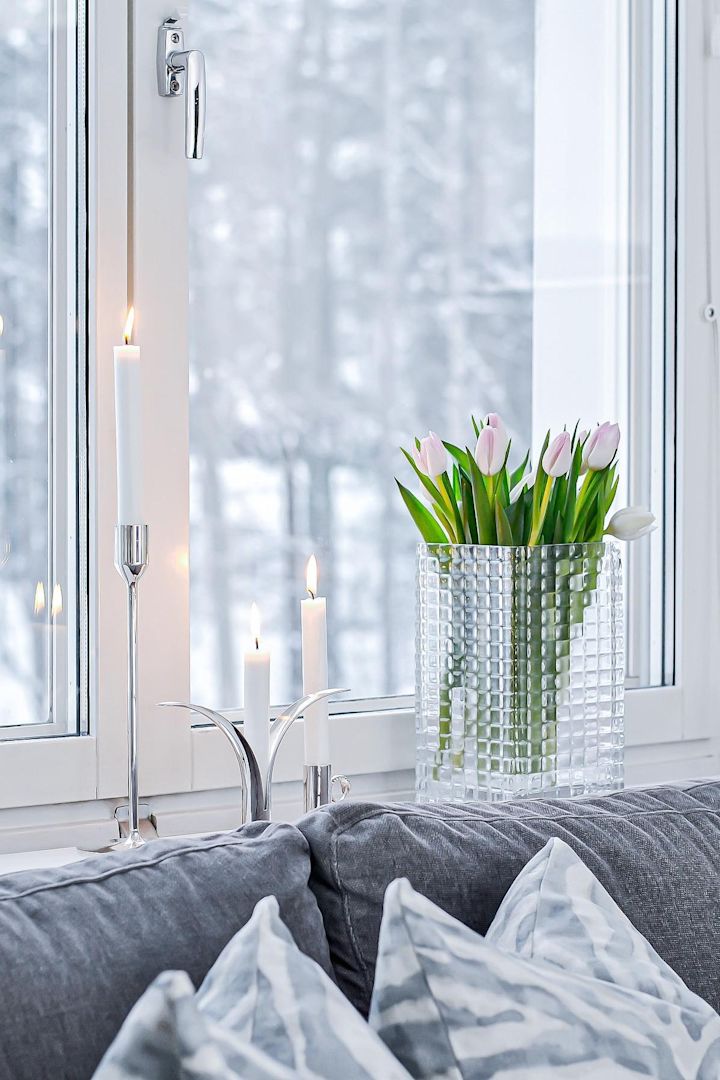 Decora el alféizar de tu ventana con velas o flores bonitas, sobre todo en los meses más oscuros. Aquí puedes ver tulipanes frescos en el jarrón City Hurricane de Louise Roe, junto a varios candelabros plateados con velas blancas en ellos en el alféizar de @josefinsinredning.