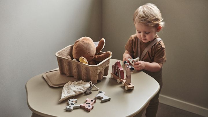 En una habitación infantil es importante dar cabida tanto a lo creativo como a lo práctico. Aquí encontramos un bebé jugando con bloques en la mesa infantil Slope en beige, de Ferm Living.