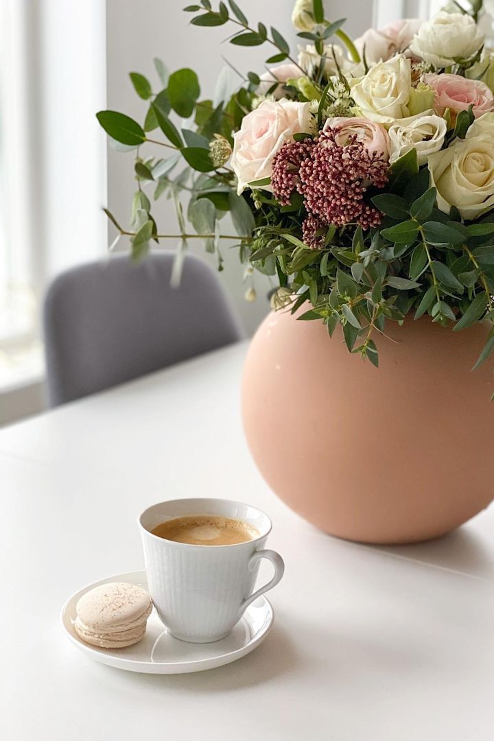 En la mesa del comedor de @helfag hay un café en la pequeña taza Grace sueca blanca de Rörstrand, al lado un ramo de flores en el jarrón Ball de Cooee Design.