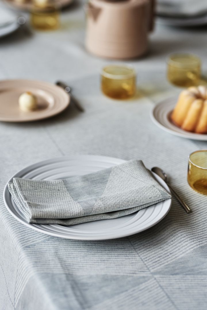 Una elegante idea para poner la mesa en suaves tonos pastel con un mantel azul cielo de NJRD y delicados elementos en beige y amarillo. 