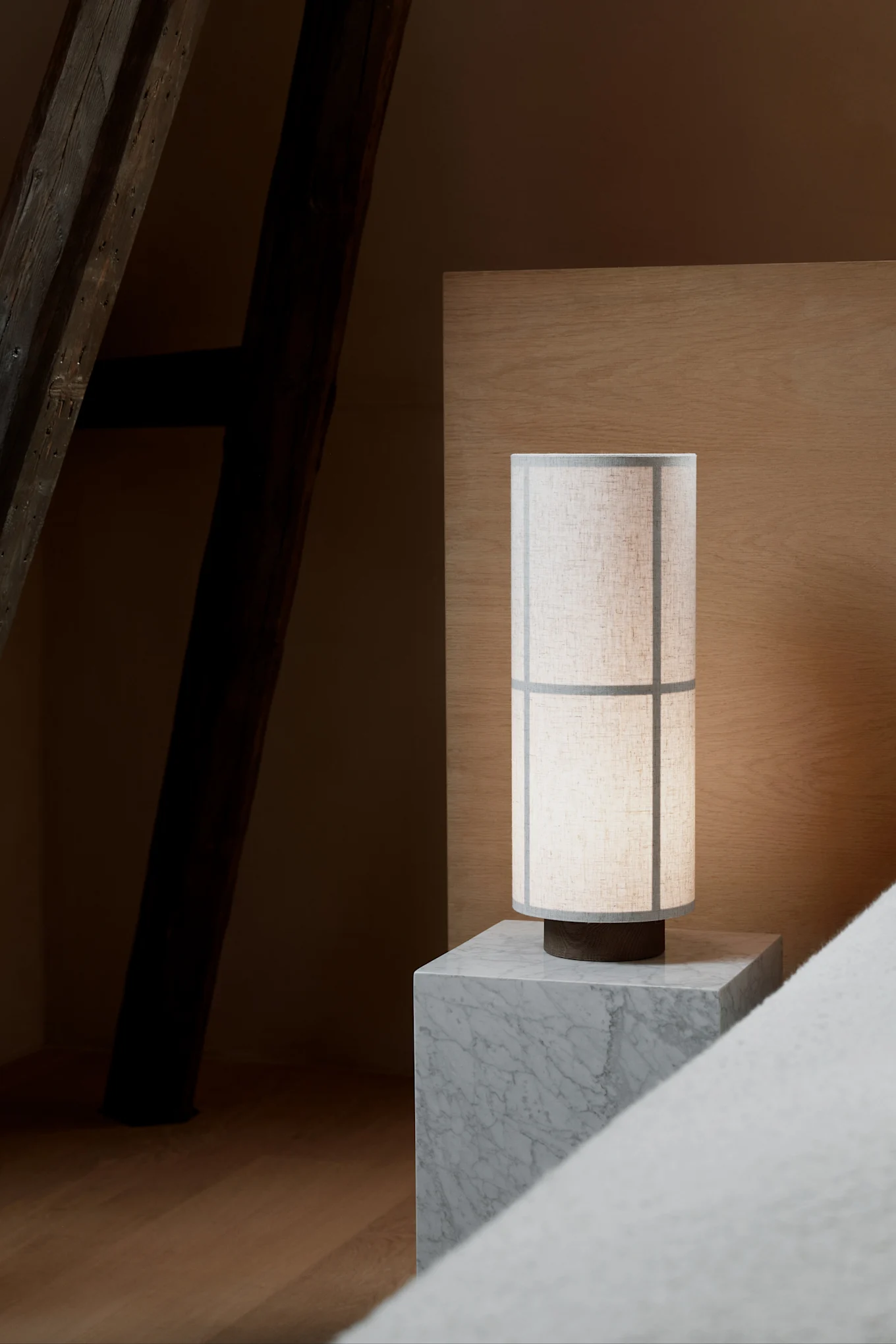 Sobre una mesita de noche de mármol gris se encuentra la lámpara de mesa Hashira de Audo Copenhagen, diseñada en estilo Japandi.