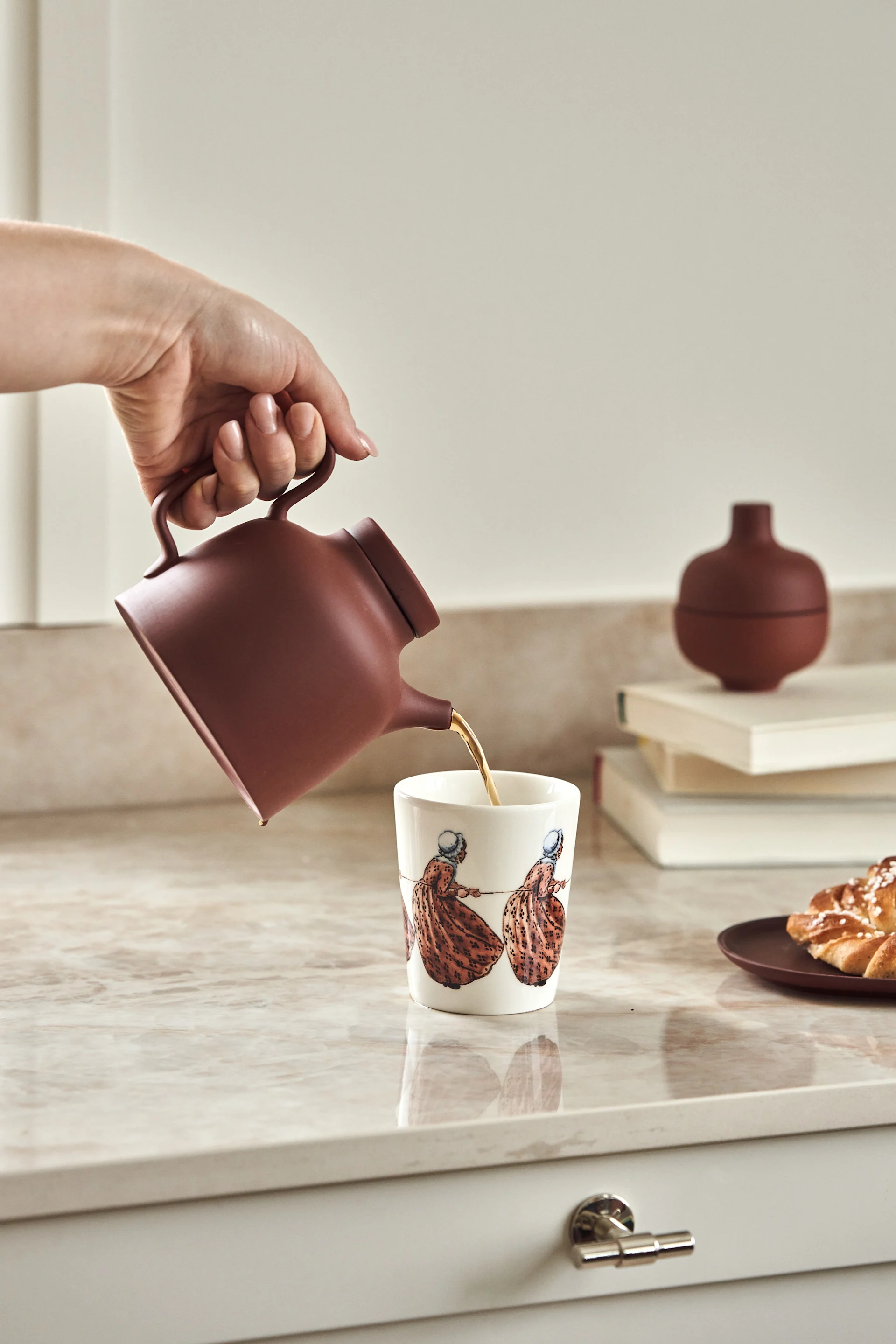 Una taza de la escritora sueca de libros infantiles Elsa Beskow, sobre una encimera de cocina, en la que se está sirviendo té.