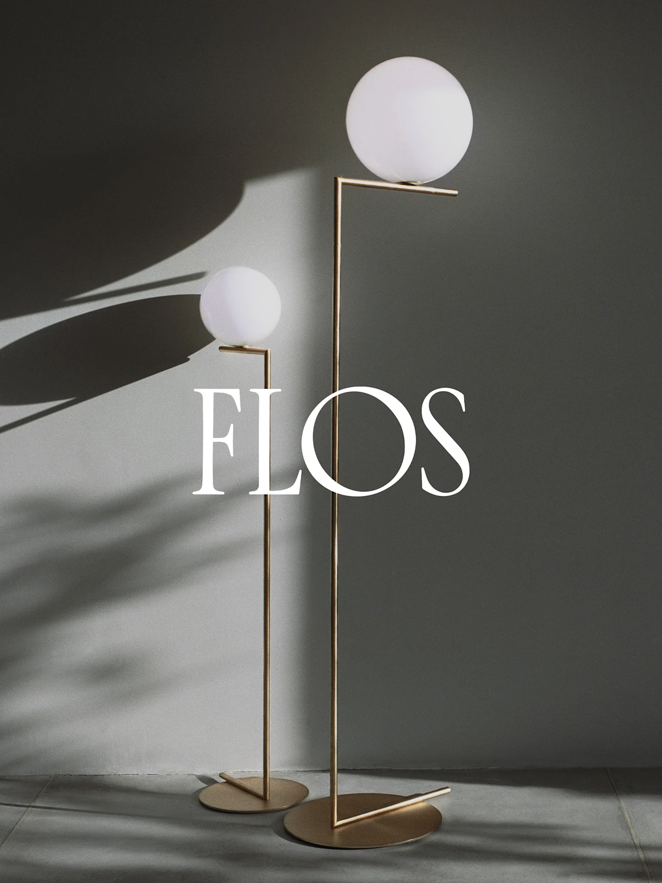 Dos lámparas de pie modernas con difusores esféricos blancos y marcos de metal dorado, con el logotipo de Flos.