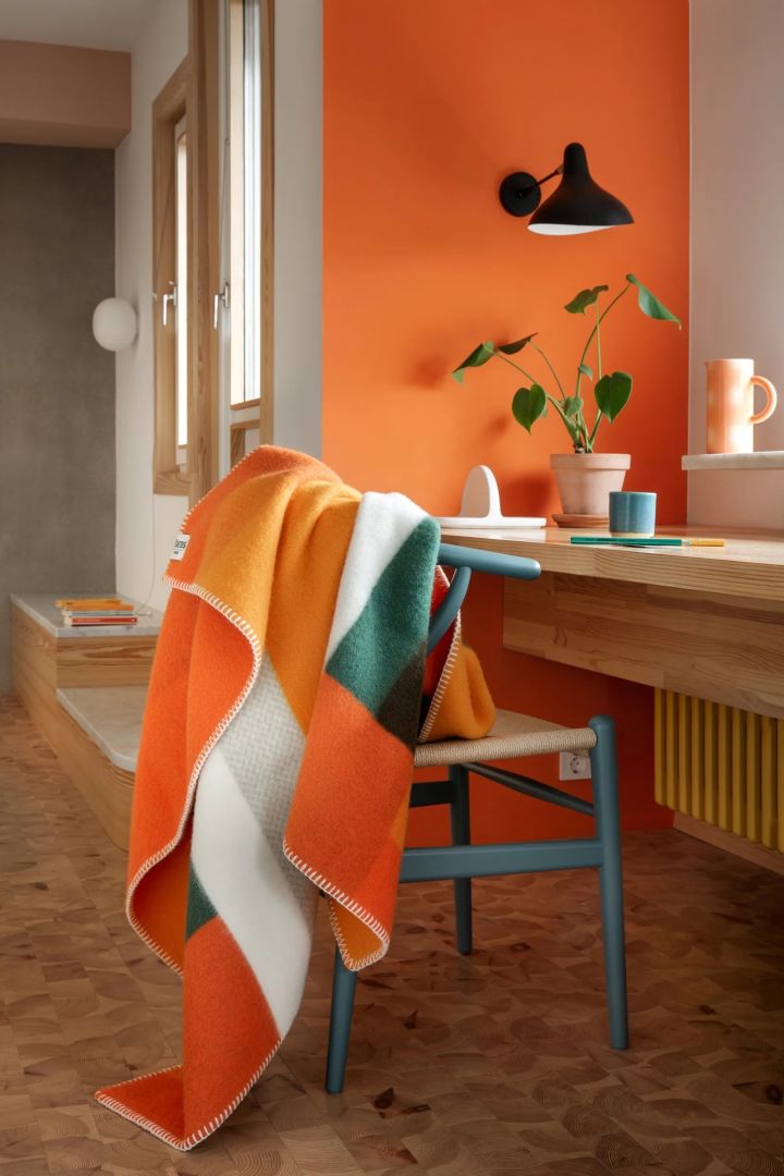 El naranja es un color fuerte en las tendencias de color para interiores de 2024. Aquí puedes ver la manta Mikkel en naranja y verde de Røros Tweed.