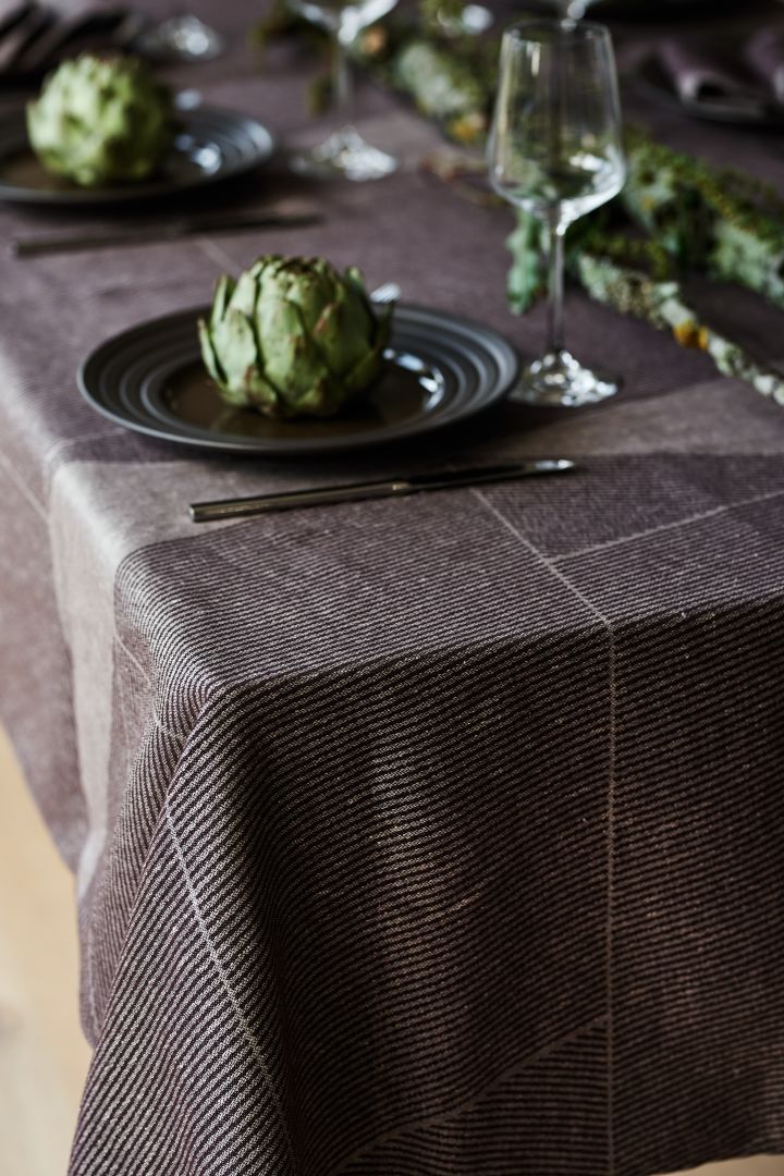 Un mantel marrón de NJRD con el plato Lines marrón también de NJRD en una mesa elegante y rústica.