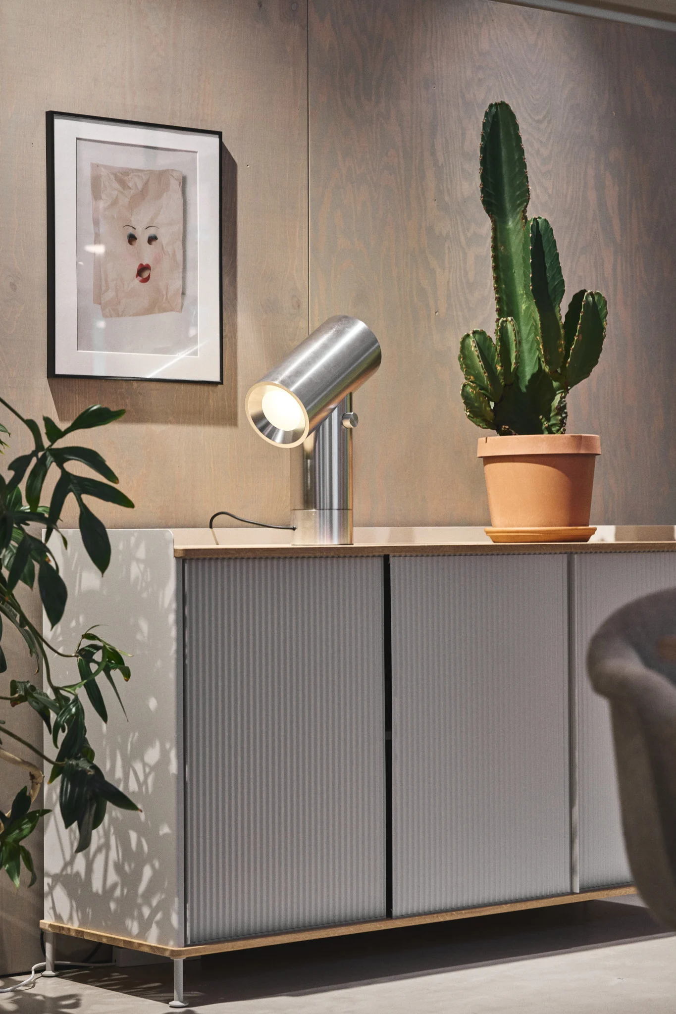 La cómoda plateada Enfold de Muuto con un cactus encima y la lámpara de mesa plateada Beam de Muuto.
