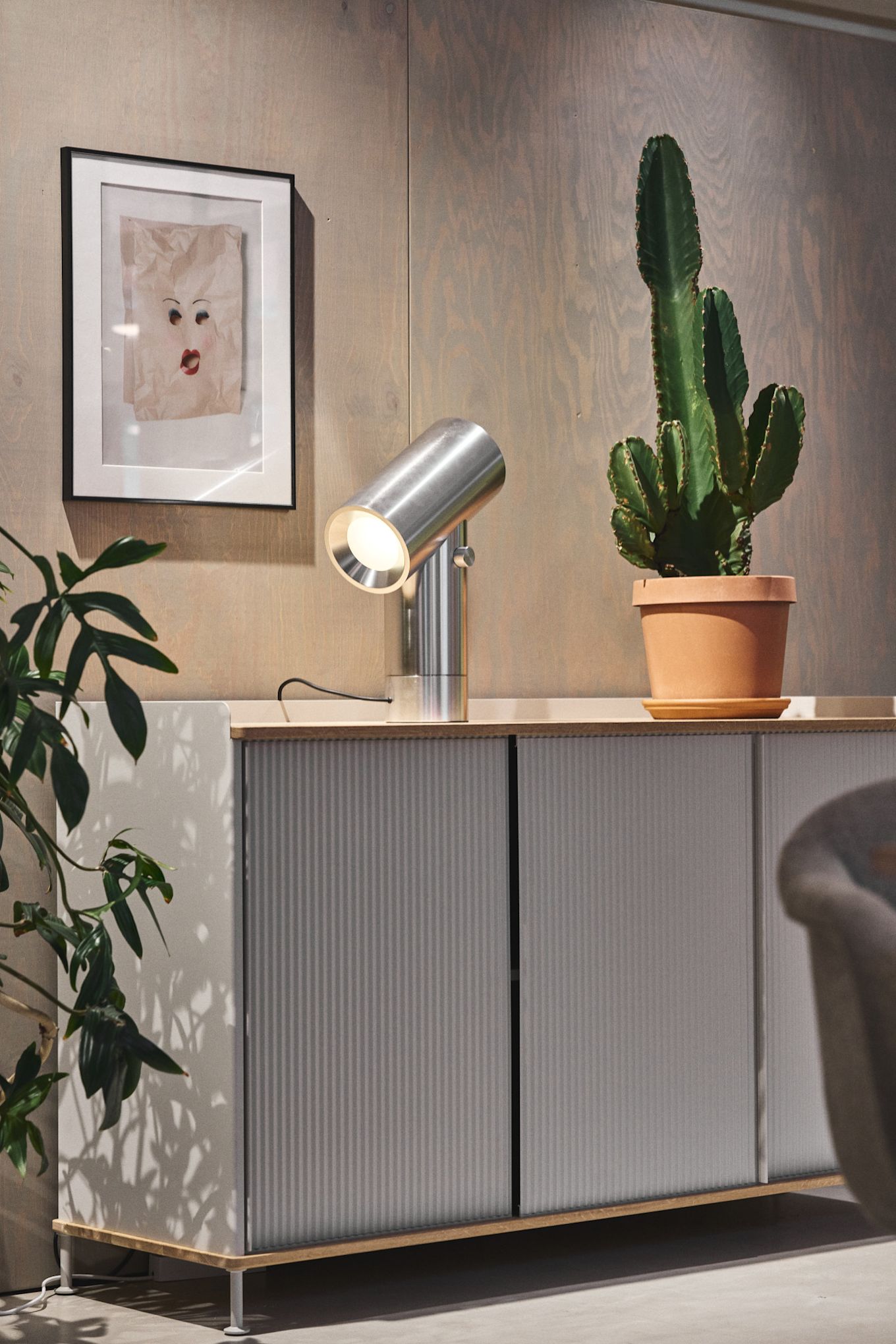 La cómoda plateada Enfold de Muuto con un cactus encima y la lámpara de mesa plateada Beam de Muuto.