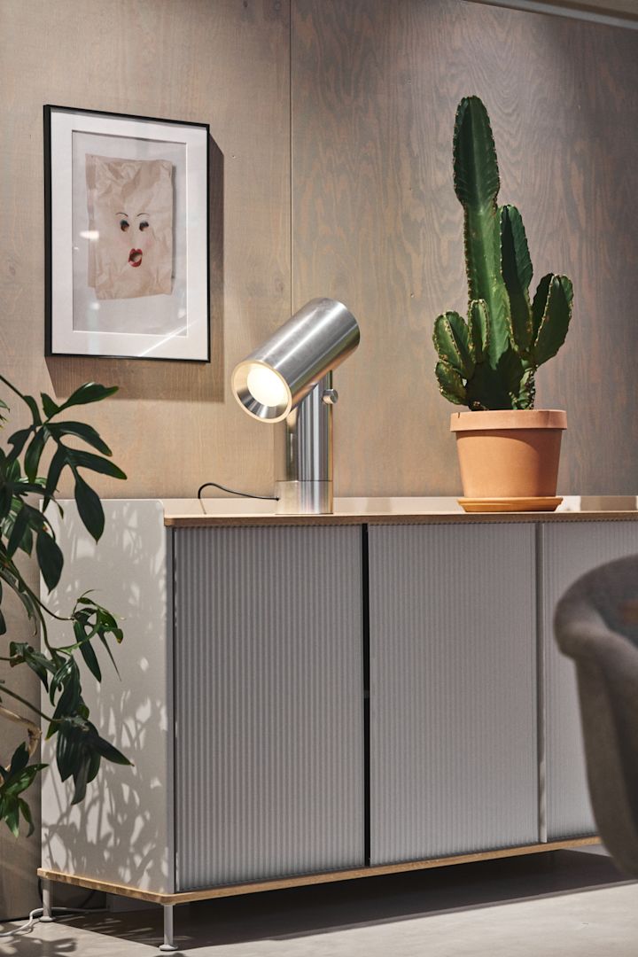 La cómoda plateada Enfold de Muuto con un cactus encima y la lámpara de mesa plateada Beam de Muuto.