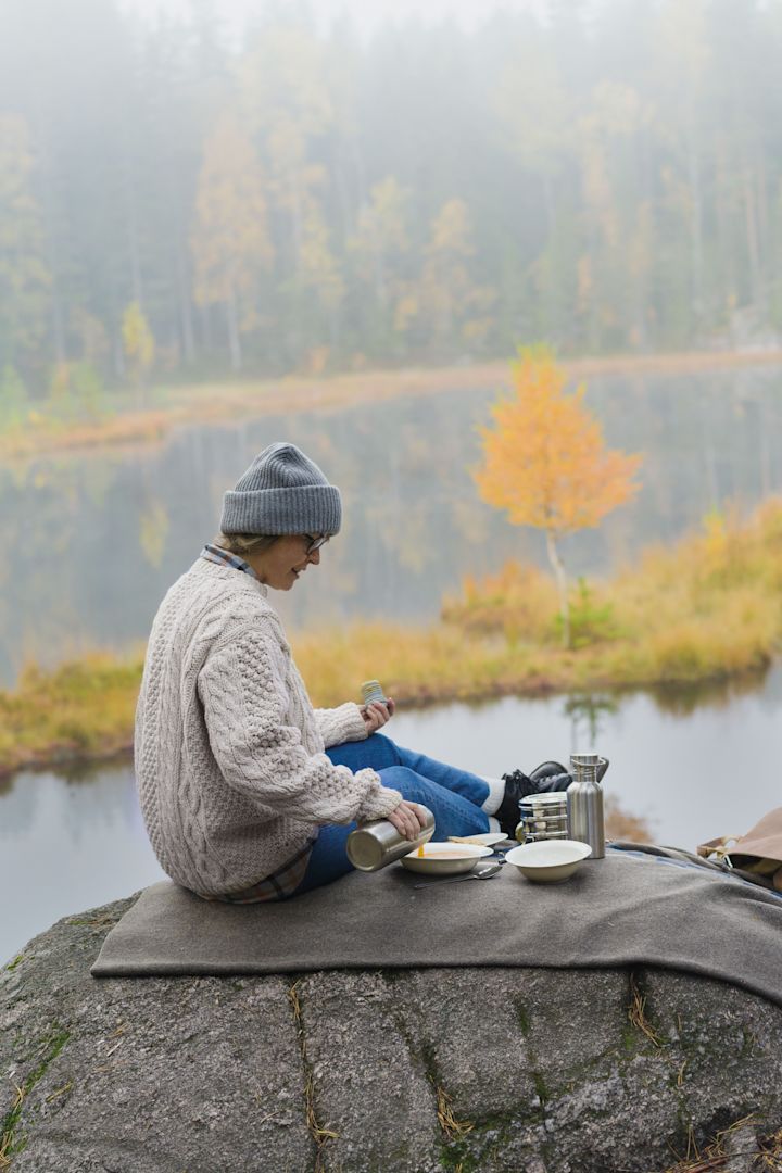 Lagom: una mujer hace un picnic en una montaña, rodeada de un paisaje otoñal.