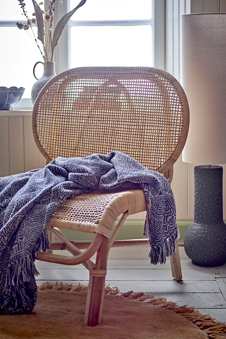 Decoración boho: la manta estampada Bresso de Bloomingville sobre un sillón de ratán.