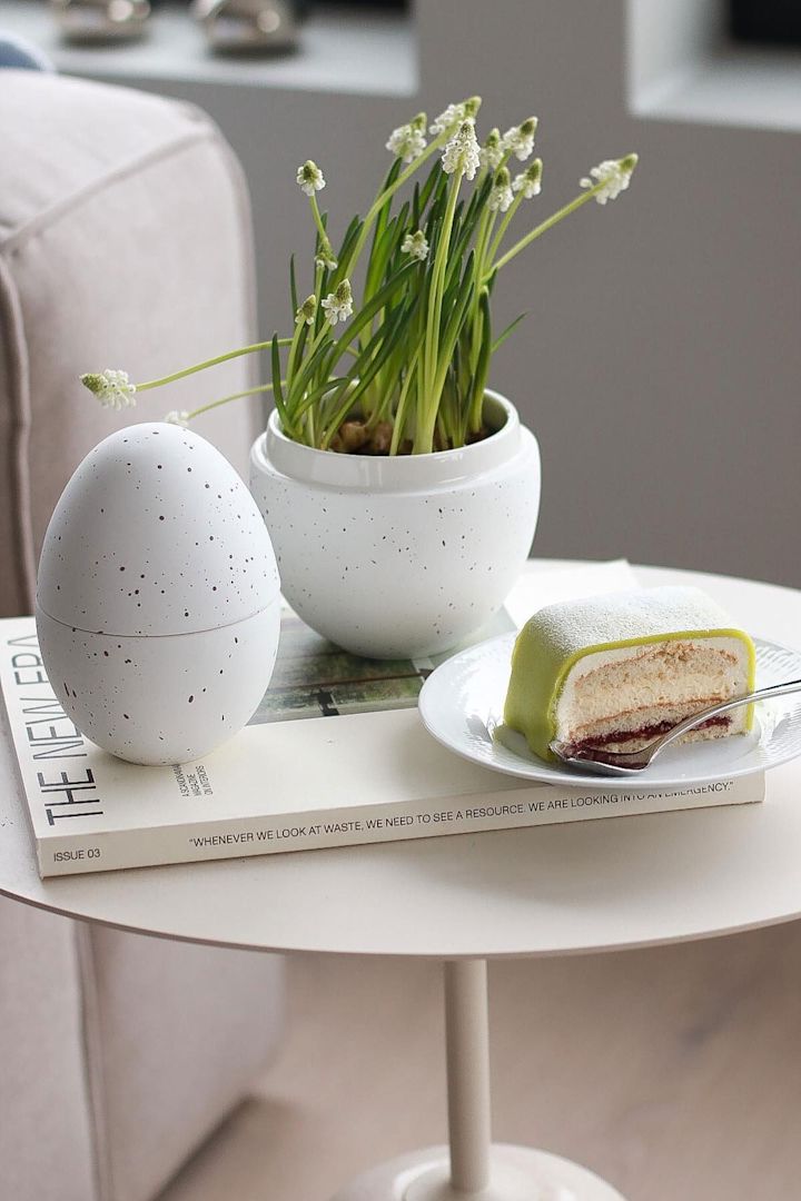 En una mesa auxiliar se encuentra la bombonera blanca con flores de Cooee Design, junto a un plato con una tarta sueca, en el hogar de @picsbyellen