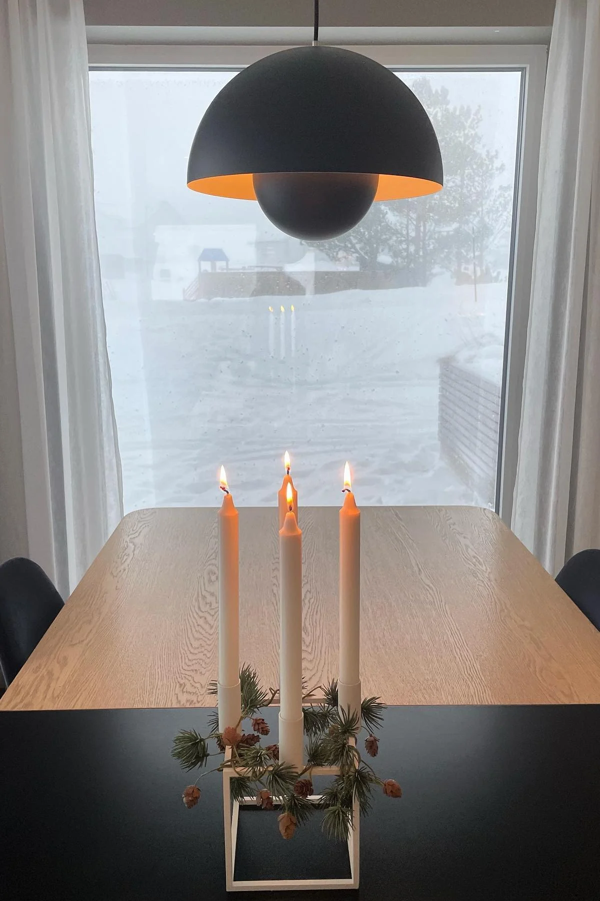 Sobre una mesa de comedor minimalista se encuentra el portavelas Kubus de Audo Copenhagen, decorado de manera sencilla.