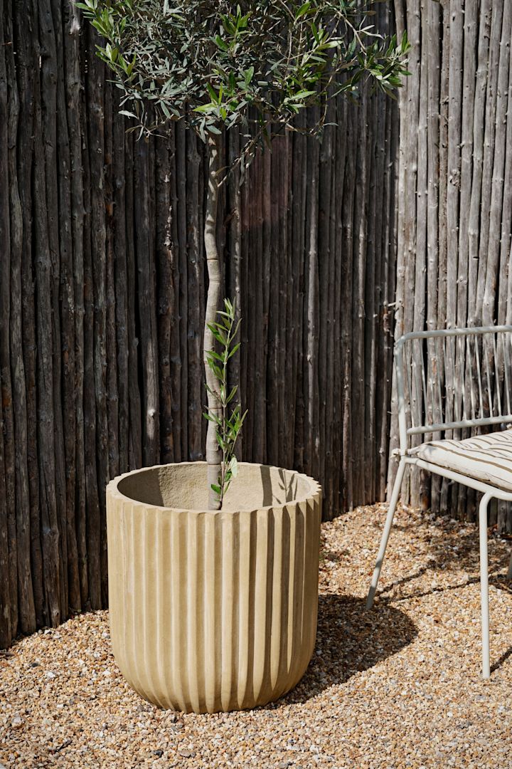 La maceta rústica Fiber para exteriores de Broste Copenhagen en un jardín.
