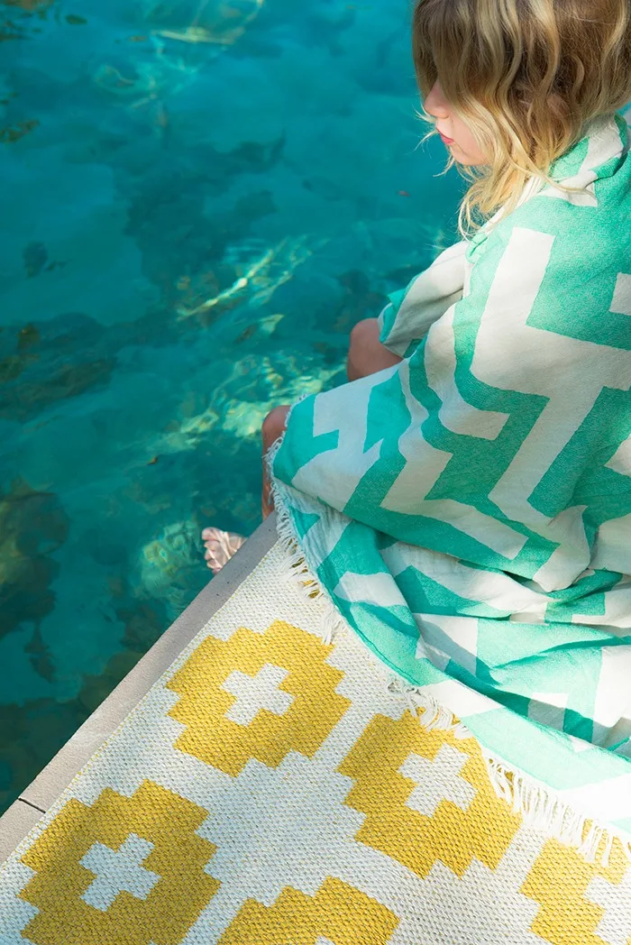 Alfombra de exterior: a la alfombra Flower de Brita Sweden no le afecta mojarse, así que puedes colocarla junto a la piscina sin problemas.