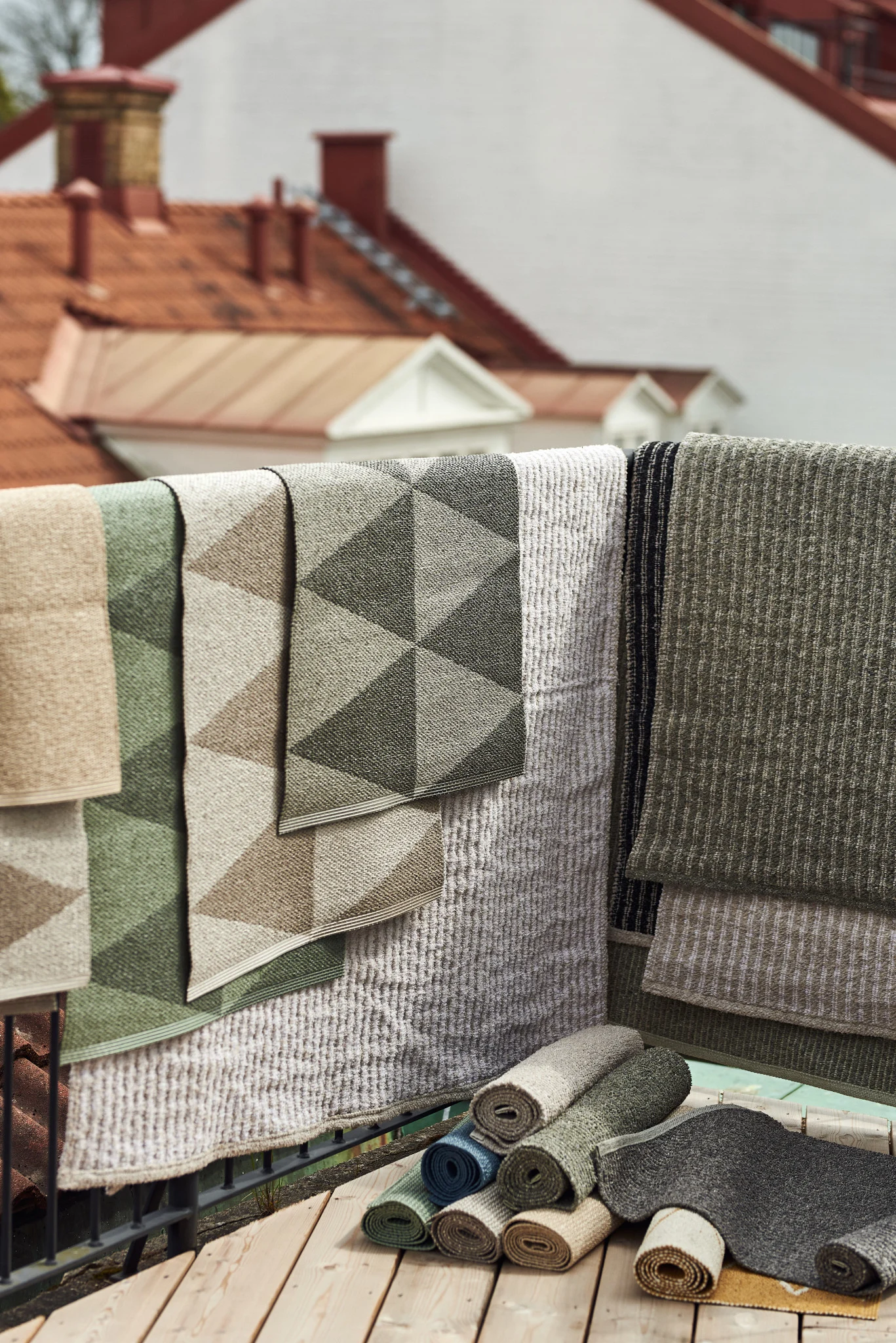 Alfombra de exterior: aquí puedes ver las numerosas alfombras de exterior de Scandi Living en varios tamaños, materiales y colores colgadas sobre la barandilla de un balcón.