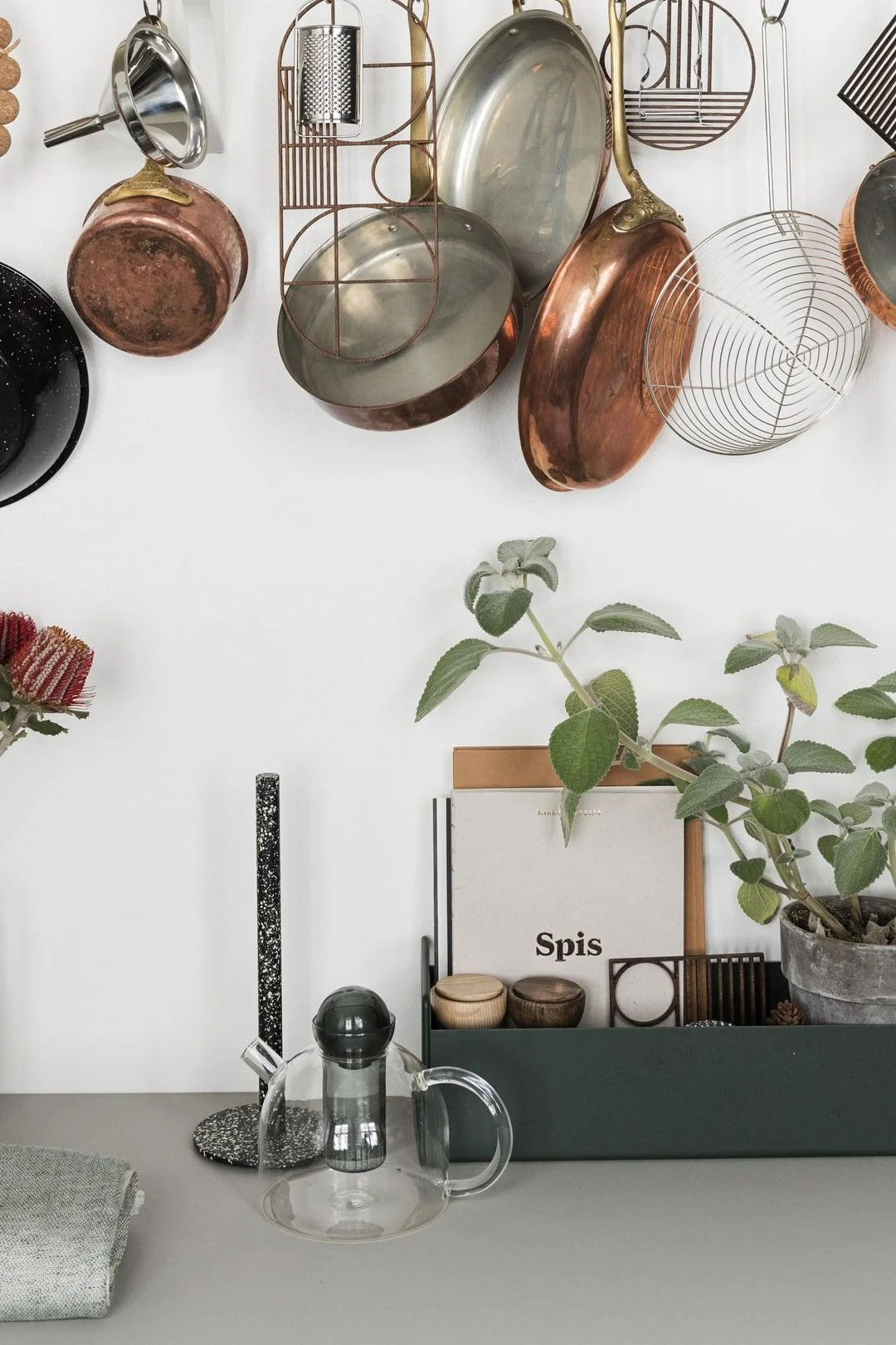 La tetera Still, de Ferm Living, es sencilla pero elegante y la encontramos colocada sobre la encimera de la cocina, con las cacerolas colgando encima.