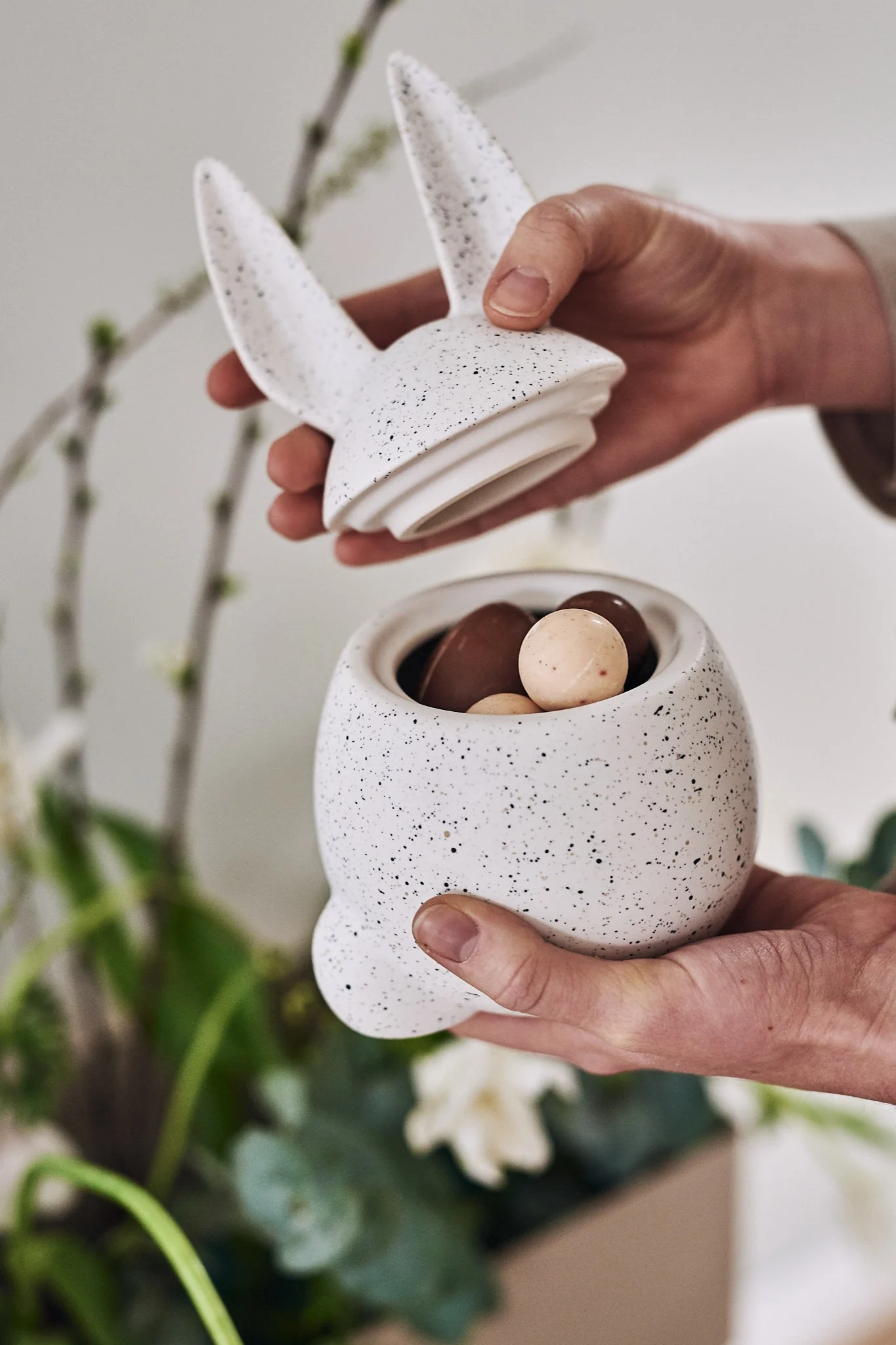 Elegante decoración de Pascua de DBKD con el cuenco Eating Rabbit lleno de huevos de Pascua de chocolate.