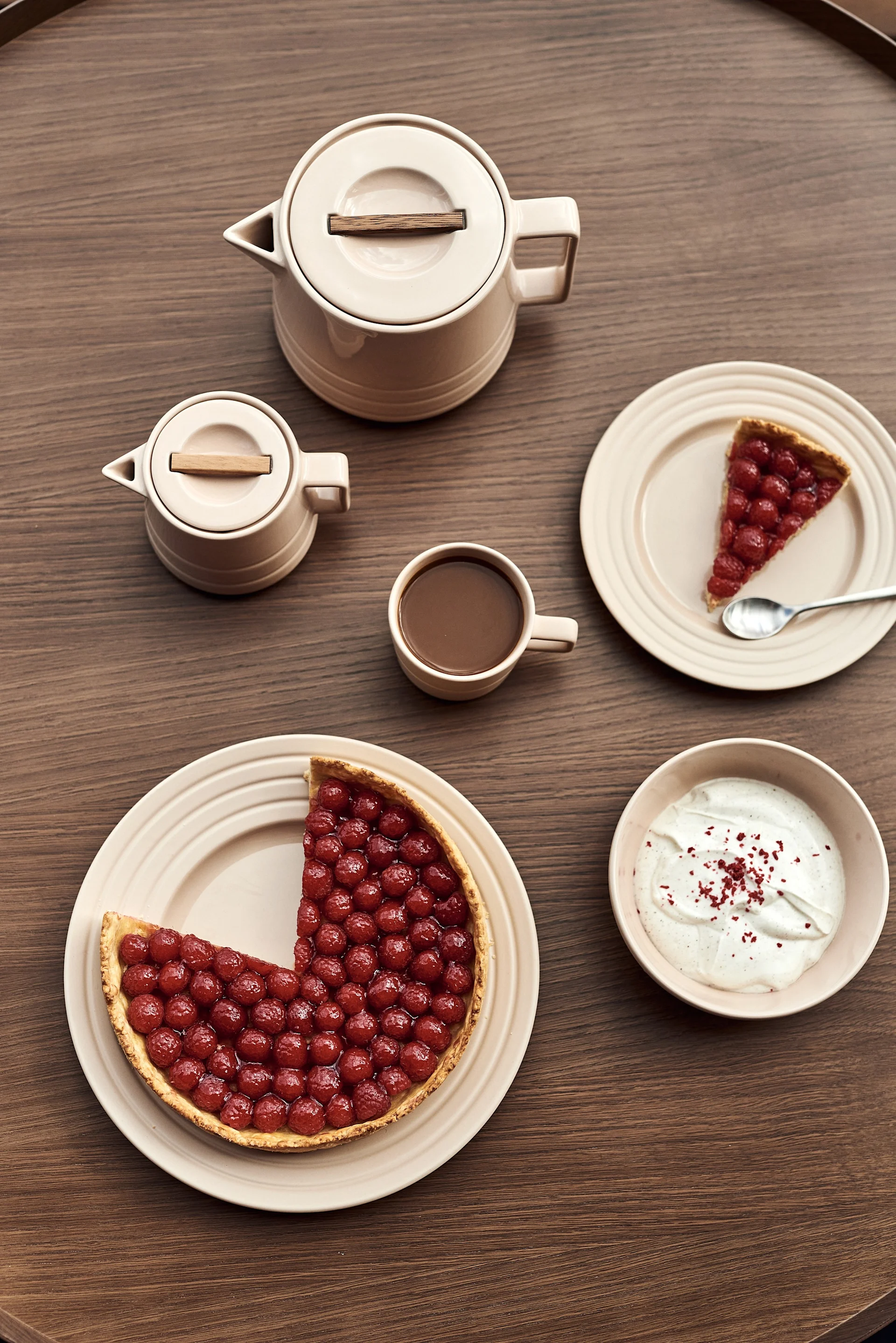 ¿Qué tal una nueva vajilla como regalo para el Día de la Madre? Aquí puedes ver platos de color beige de varios tamaños con pasteles, una taza, una tetera, un cuenco y una jarra de la colección Lines de NJRD.