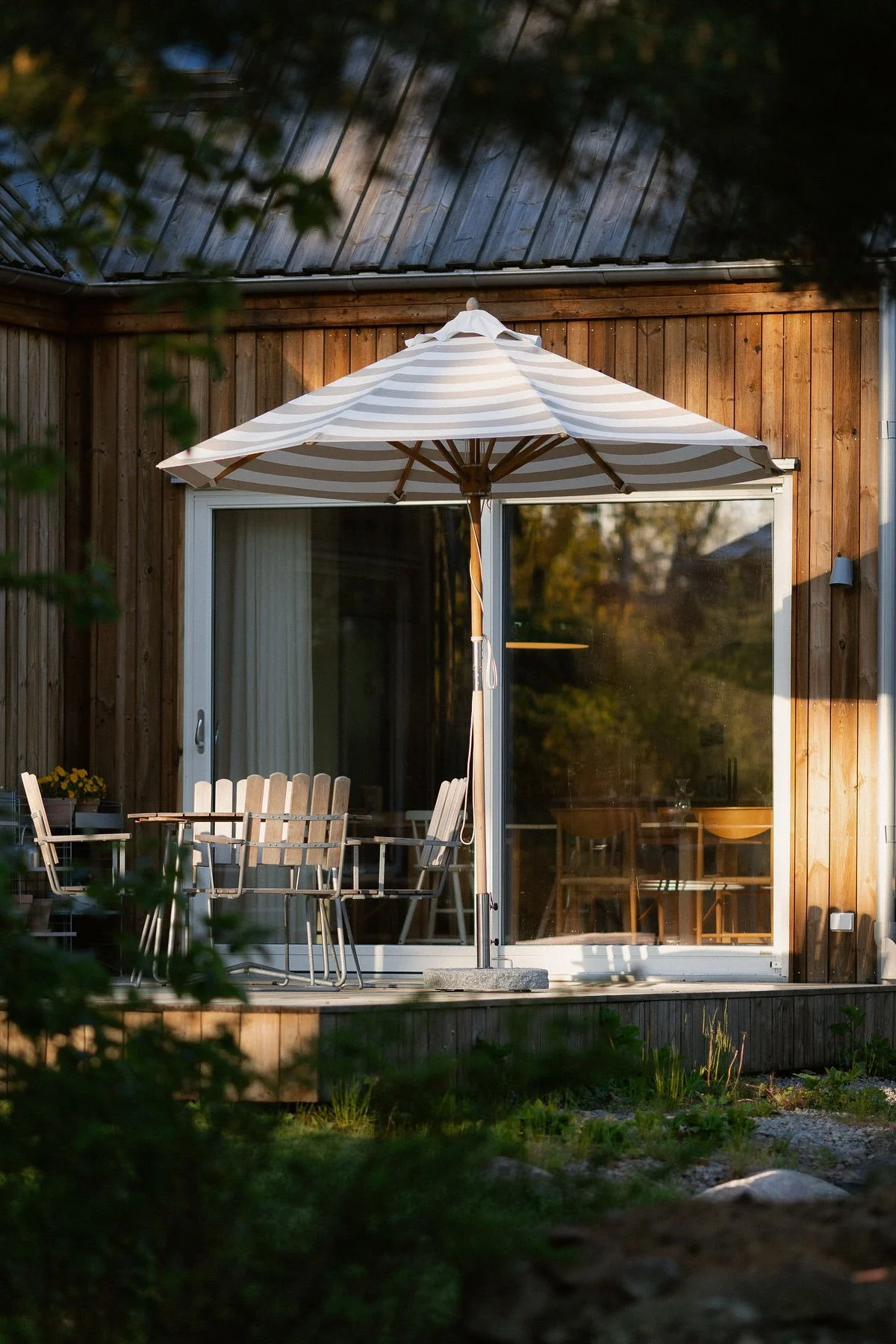 Delante de la casa de madera y en la terraza de @applauden se encuentra la sombrilla Hisshult de 1898, junto a la que hay un grupo de sillas de Grythyttan.