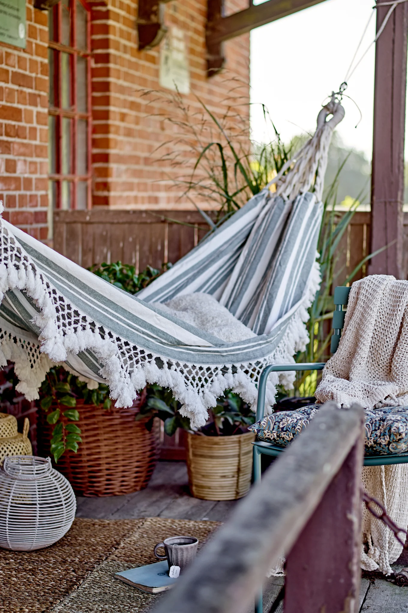 Decoración de balcón boho: la hamaca Cruz de Bloomingville cuelga en un balcón decorado al estilo boho.