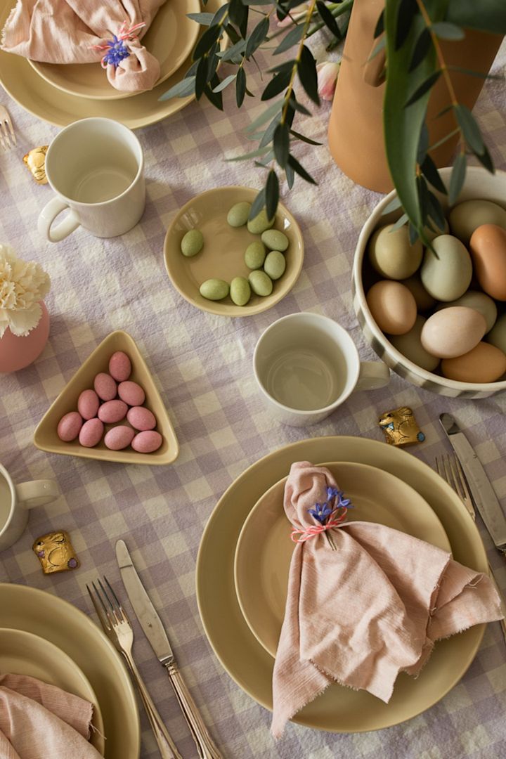 Las mejores ideas para la mesa de Pascua siempre incluyen un bonito doblado de servilleta, como este, con un sencillo recogido y una flor alrededor de una servilleta de lino rosa de Scandi Living.
