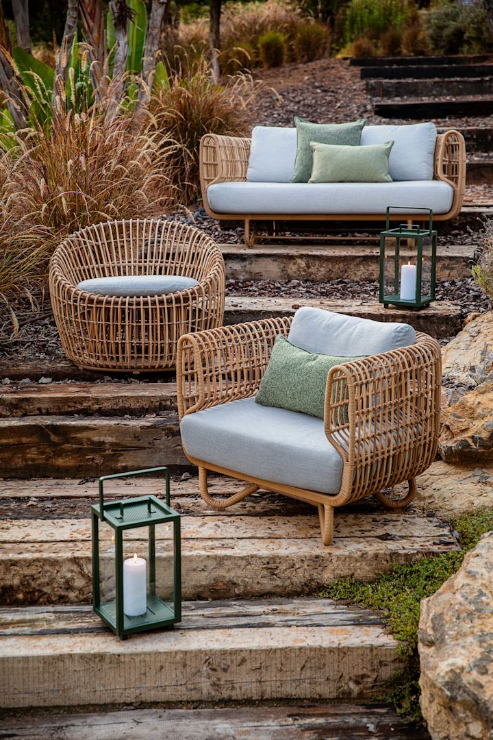 El sillón lounge Nest de Cane-line, colocado sobre una escalera, destaca por su elegante forma orgánica. Este diseño lo convierte en un ejemplo perfecto de las tendencias en muebles de jardín 2025.
