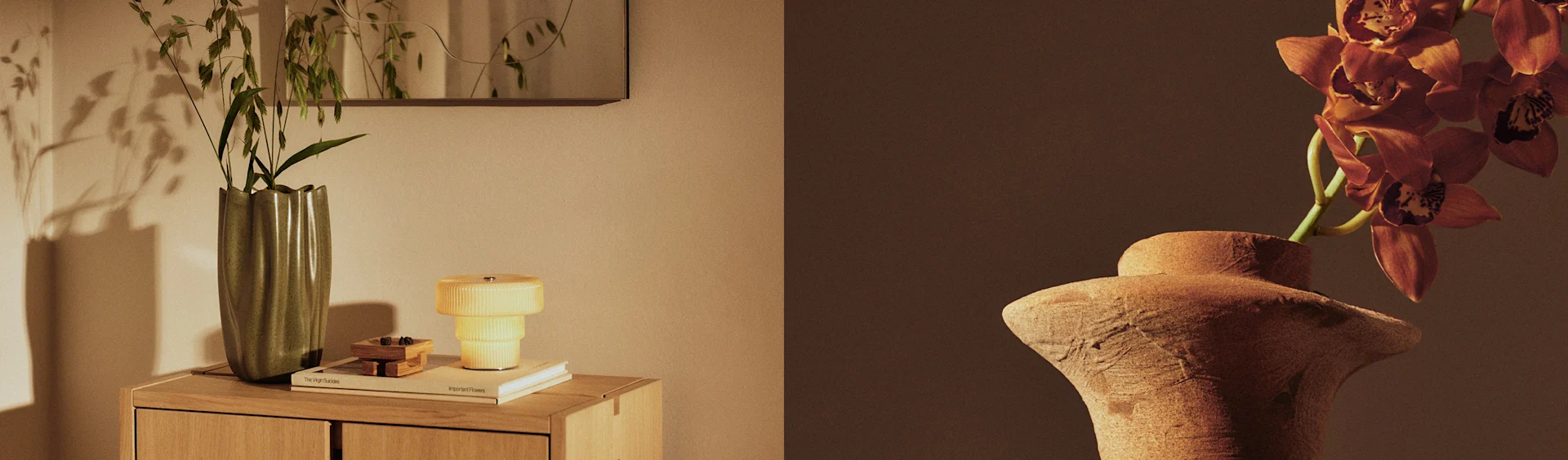 Dos jarrones exhiben plantas, un jarrón verde con follaje sobre un mueble junto a una lámpara amarilla, y un jarrón de terracota con orquídeas naranjas.
