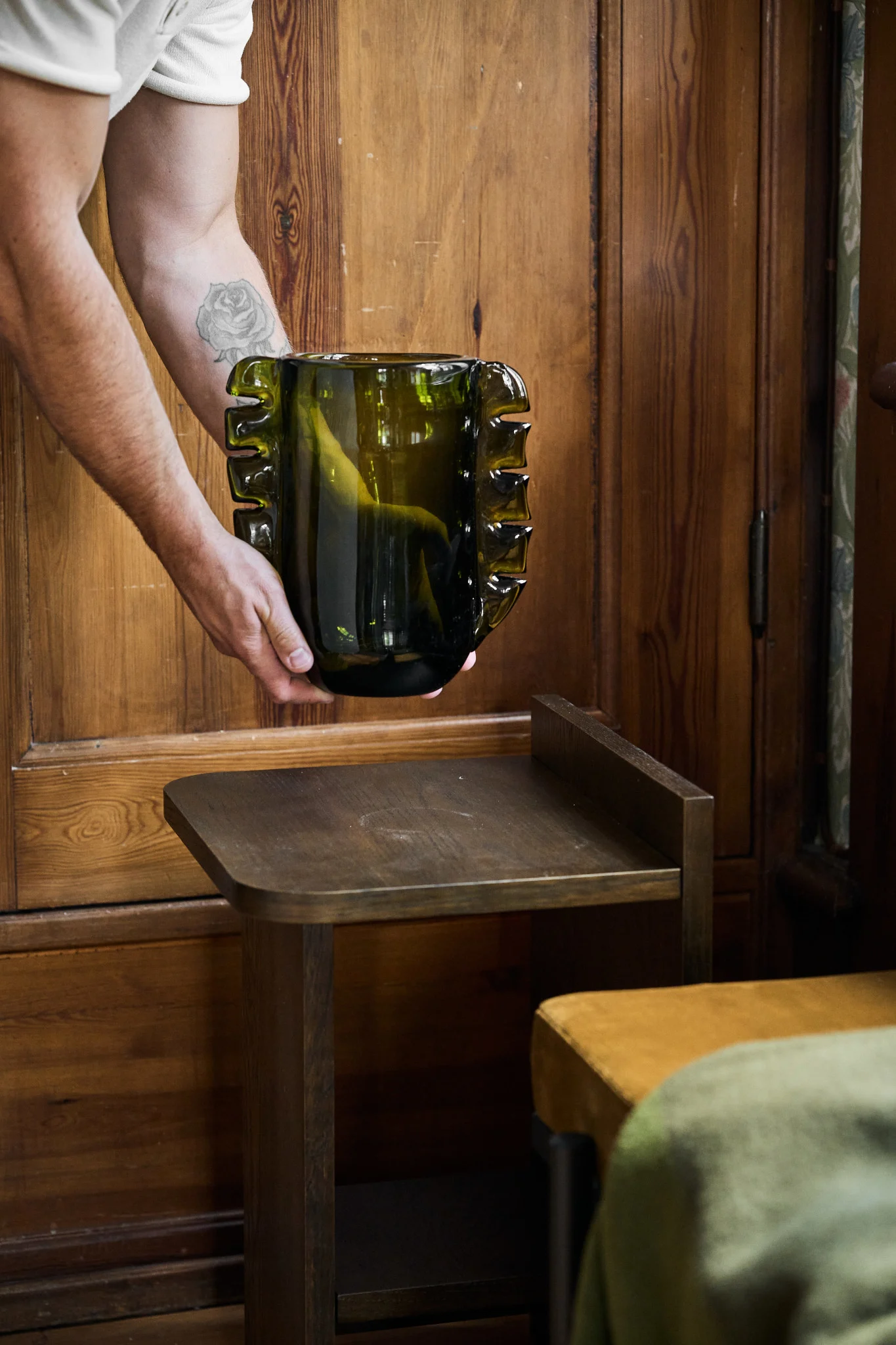 El verde oliva es uno de los colores tendencia para nuestros interiores en 2026. Aquí se puede ver un jarrón colocado sobre una mesita auxiliar.