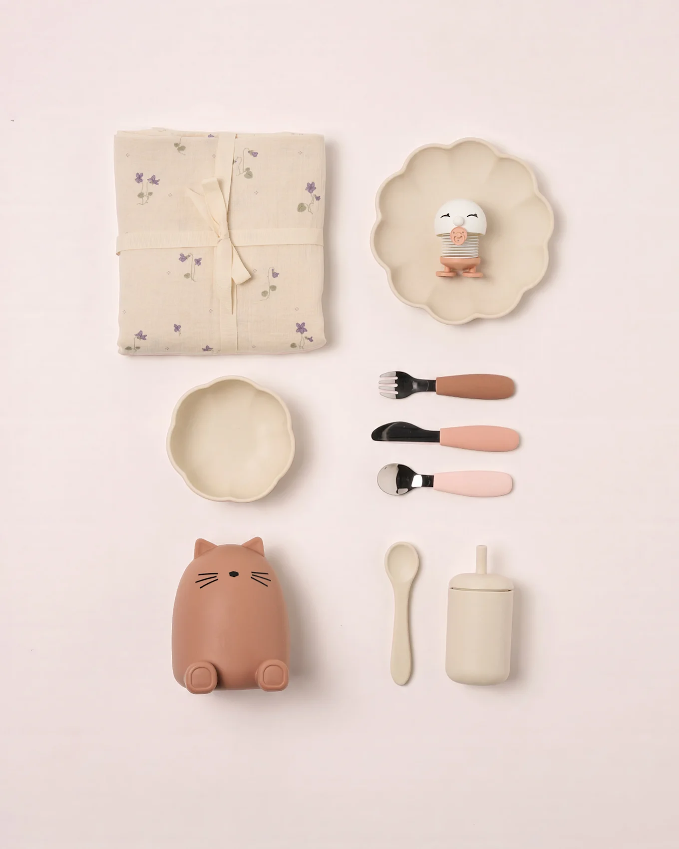 Set de bebé: manta floral, plato festoneado con juguete pájaro, cuenco, recipiente gato, cubiertos, cuchara y taza con tapa.
