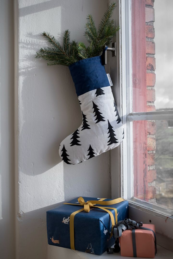 Manualidades navideñas con ramas de abeto: aquí se ve el gran calcetín de Navidad de Fine Little Day, decorado con ramas de abeto, colgado en una ventana.