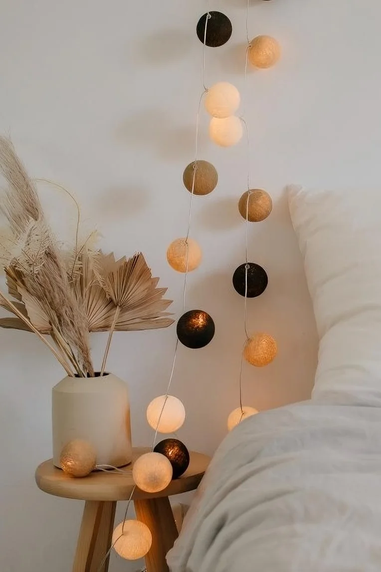 Con sus tonos beige y marrón, la cadena de luces Biscotti de Irislights, que aparece aquí colgada junto a una cama, es la decoración boho perfecta.