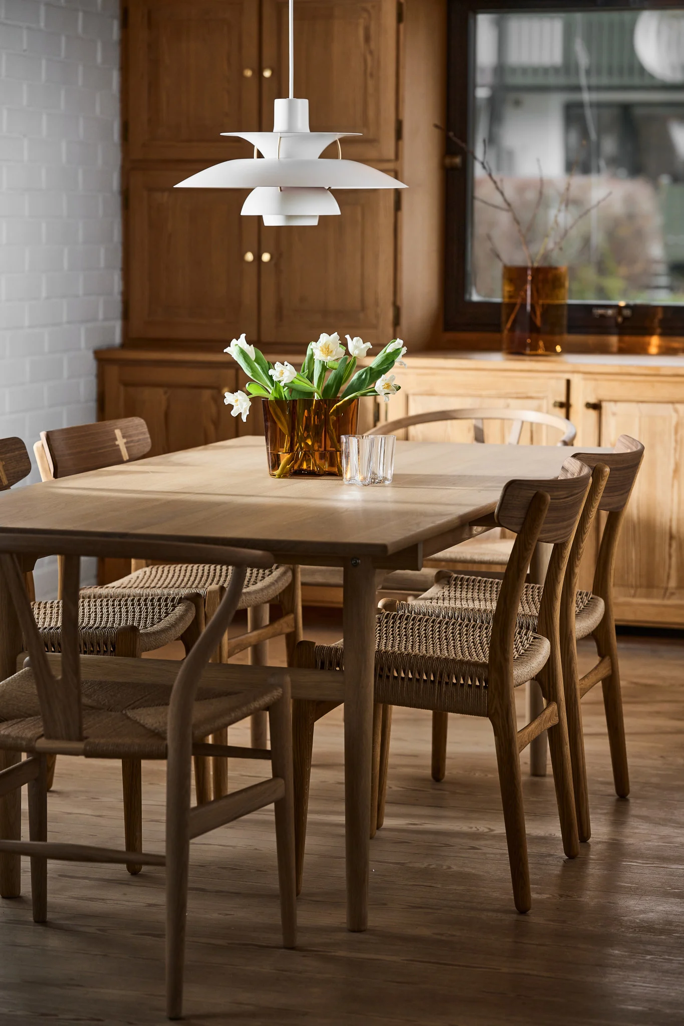Lámparas escandinavas: La lámpara colgante blanca PH 5 de Louis Poulsen se encuentra sobre una mesa de comedor en un comedor decorado al estilo escandinavo.