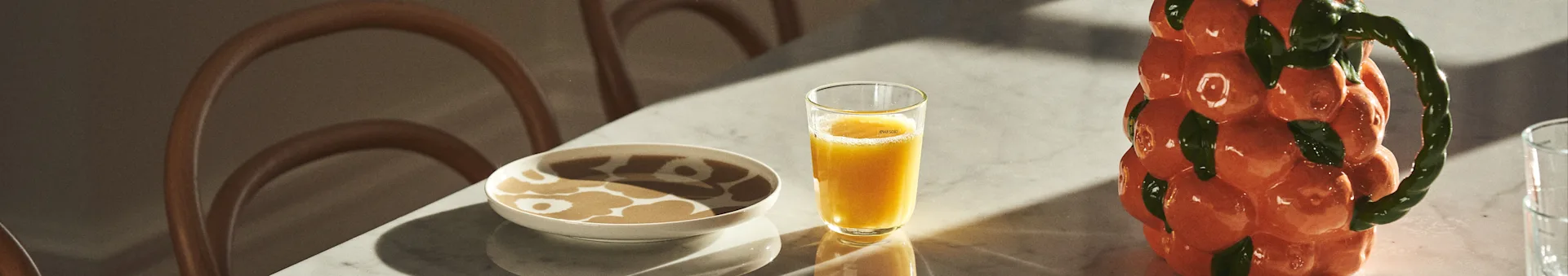 Mesa puesta con vajilla de Marimekko, zumo y jarra de BYON con diseño de mandarinas.
