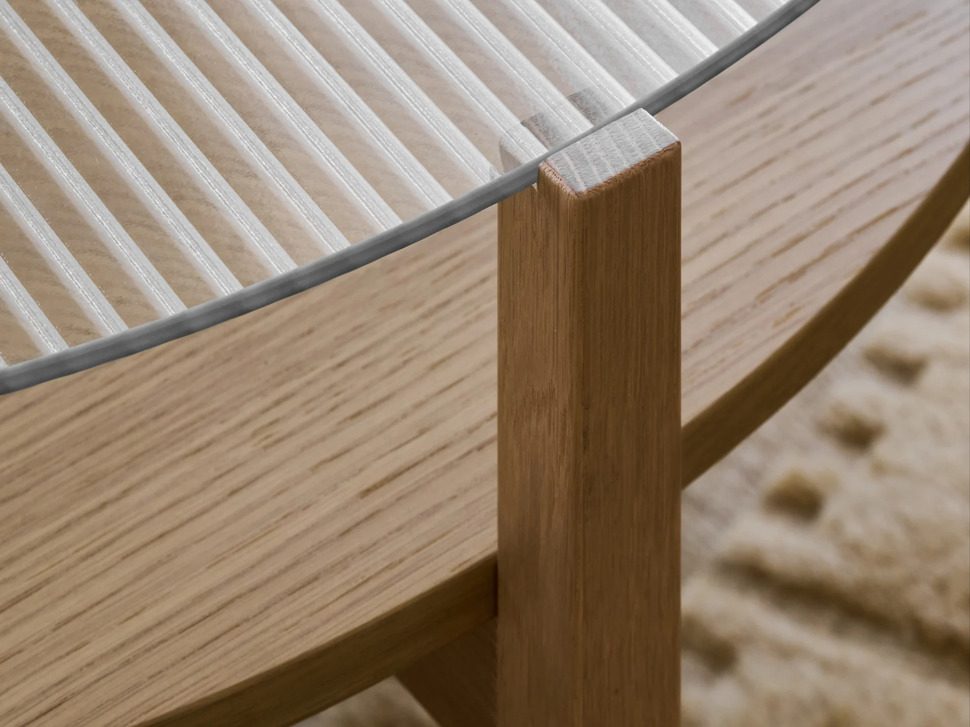 Primer plano de una mesa con tapa de cristal acanalada y pata de madera de color marrón claro.