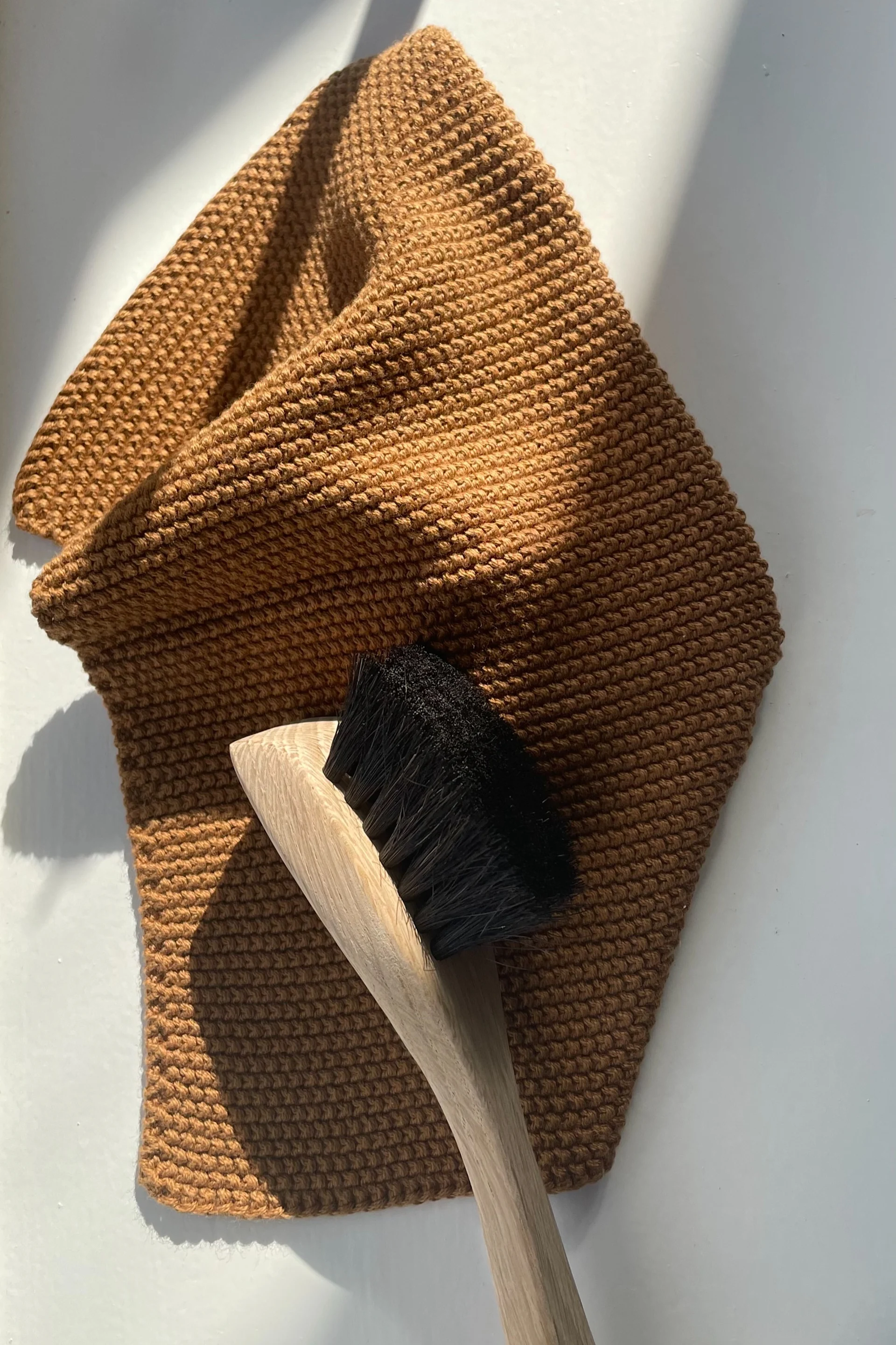 Limpia tu sartén con un cepillo para lavar, que está colocado sobre un trapo de cocina marrón, ambos de Humdakin.