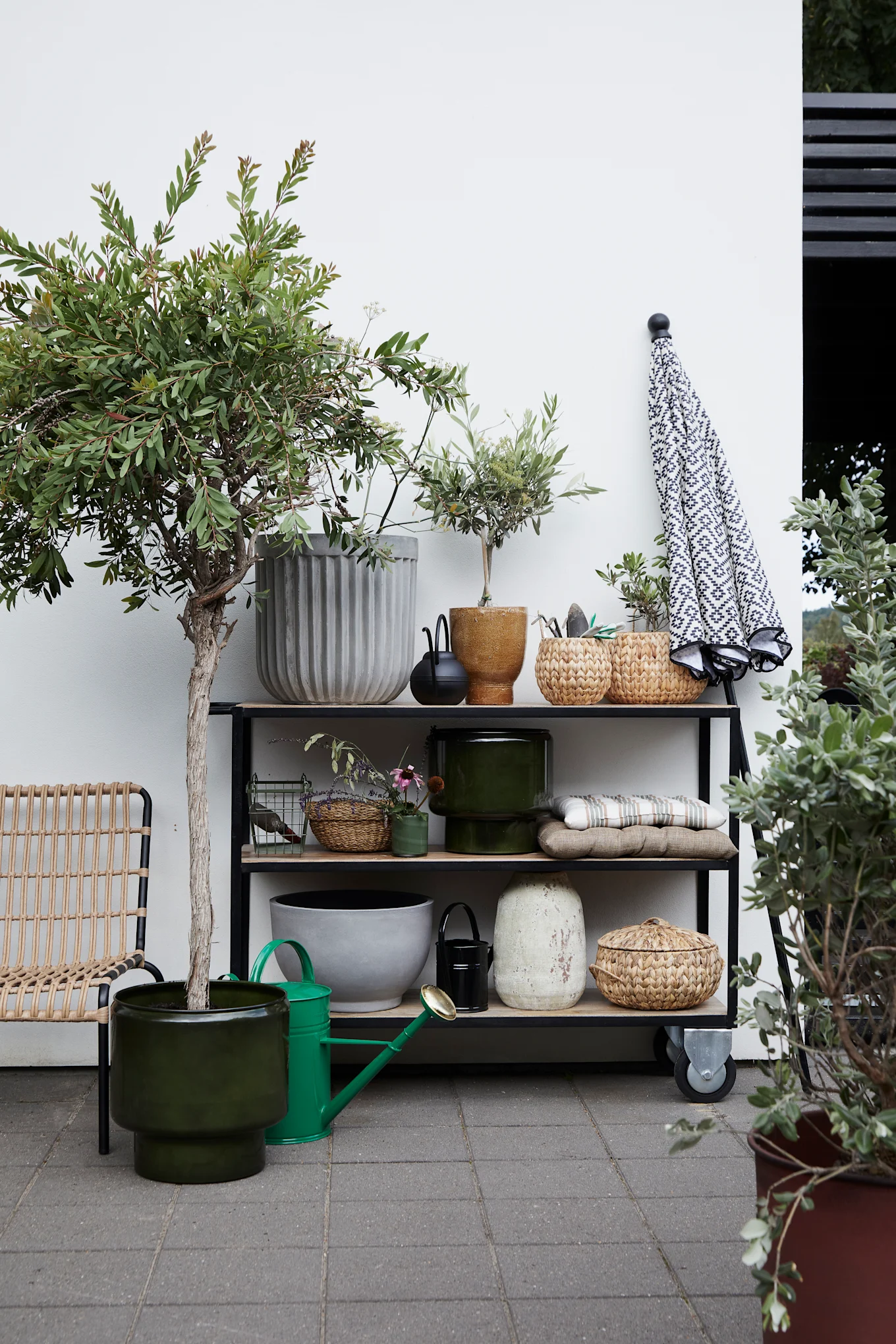 Muchas plantas aportan el estilo boho adecuado a tu balcón. Aquí puedes ver un soporte para plantas con varias flores en macetas de House Doctor.