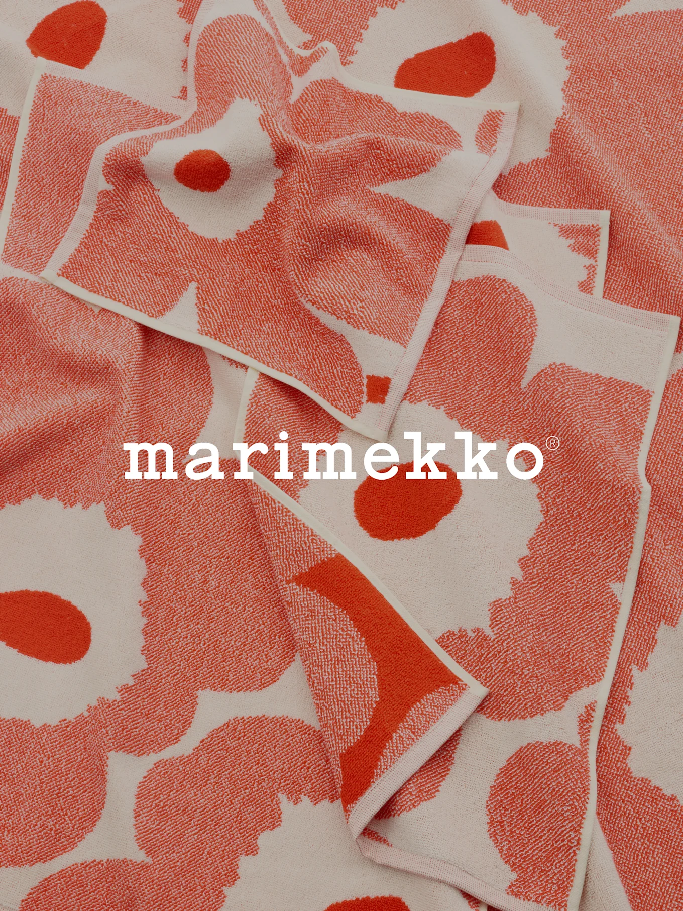 Toallas plegadas de coral y blanco roto con estampado y el logo de Marimekko.