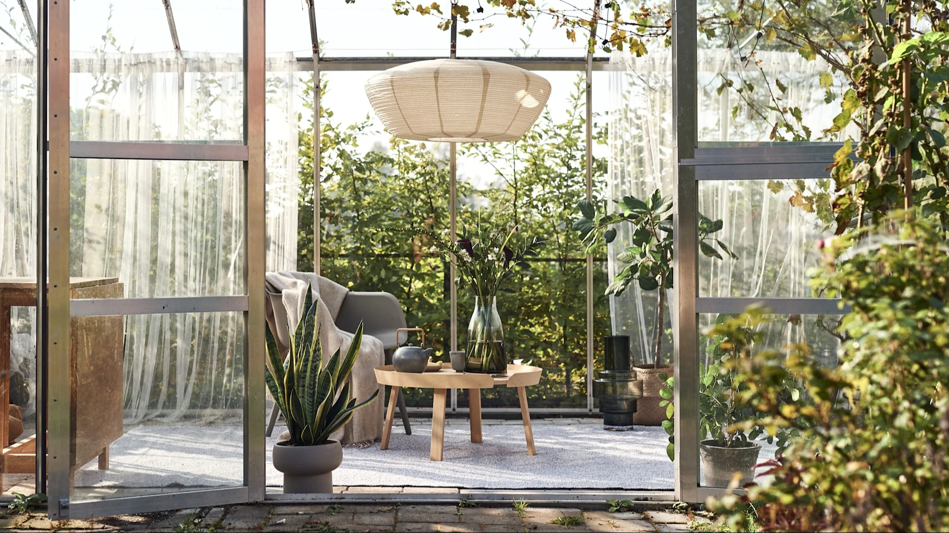 Alfombra de exterior: aquí puedes ver un invernadero que se ha transformado en una acogedora sala de estar con una lámpara colgante, una silla, una mesa auxiliar y una gran alfombra de exterior.