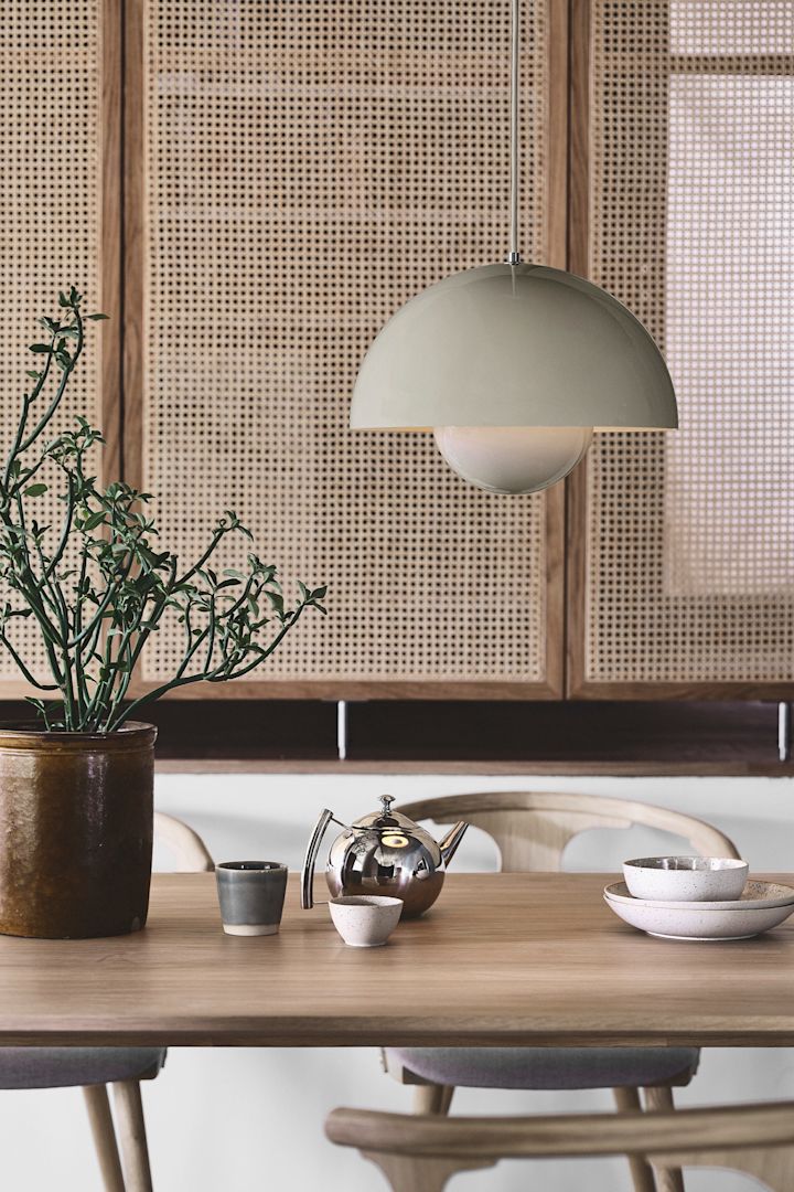 Disfruta de la tendencia Japandi con accesorios sencillos y claros como la lámpara colgante VP7 Flowerpot de &Tradition en beige, aquí la ves colgando en un entorno de comedor con una pared de ratán.