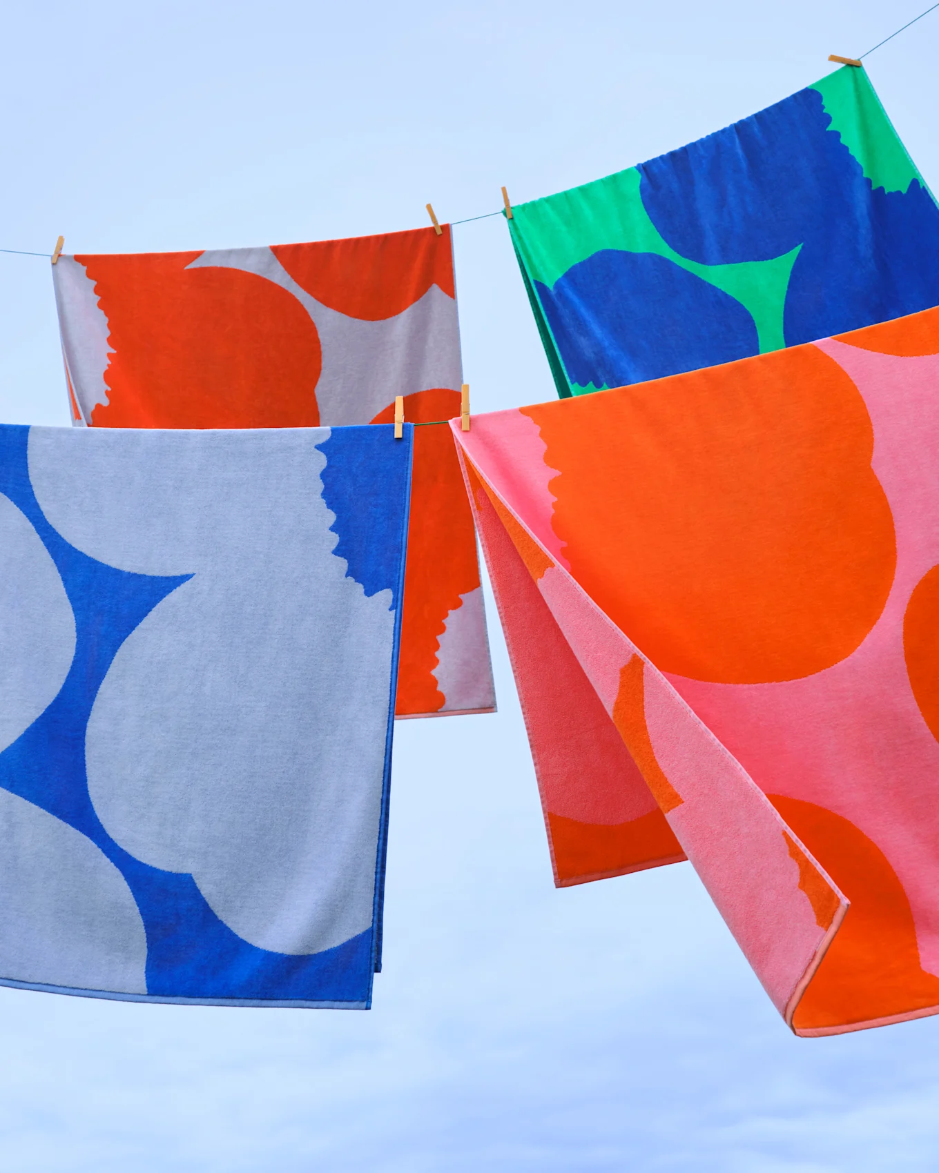 Toallas coloridas con patrones cuelgan de un tendedero contra un cielo azul.
